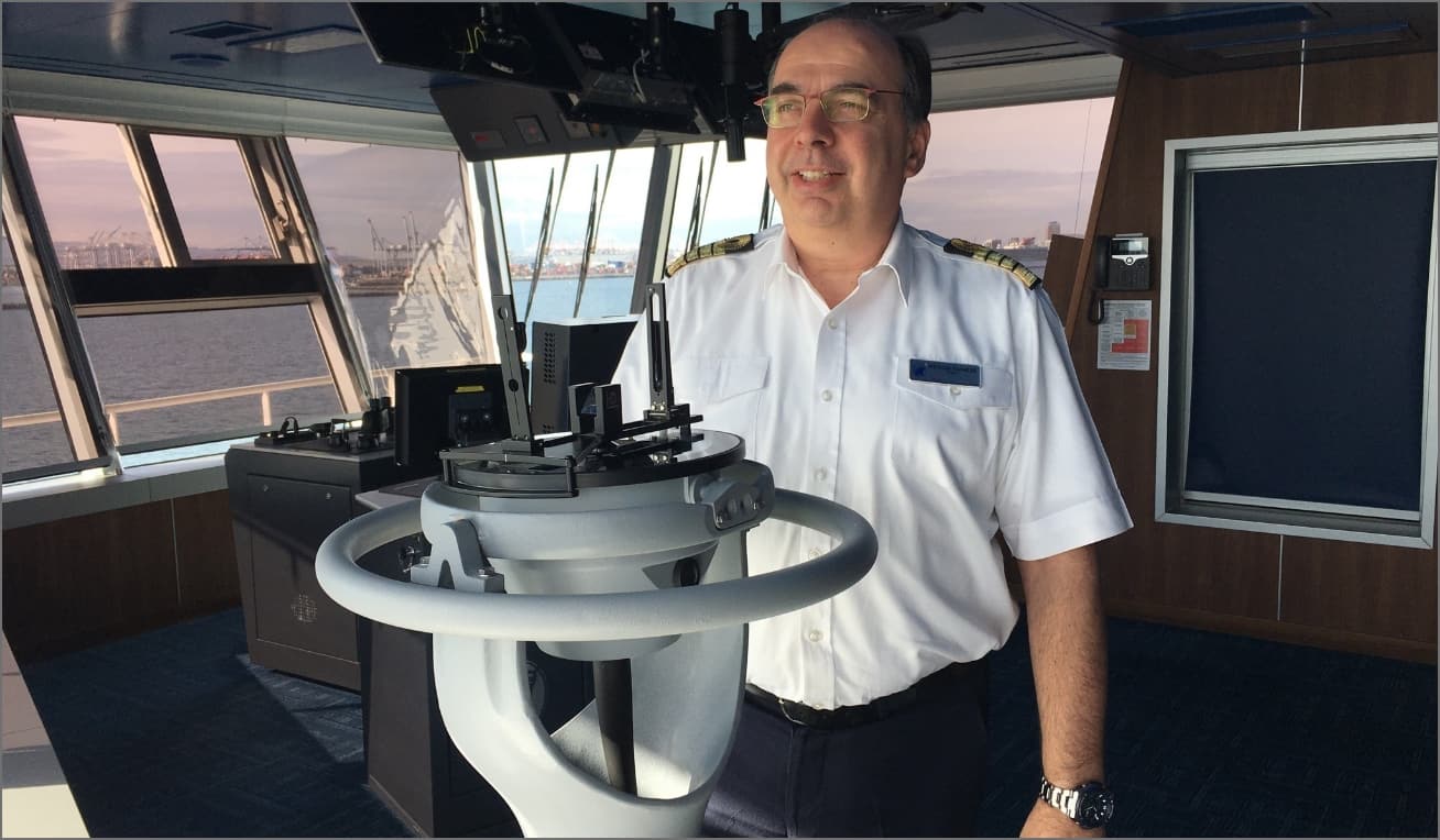 A Holland America Line captain standing at the ship helm
