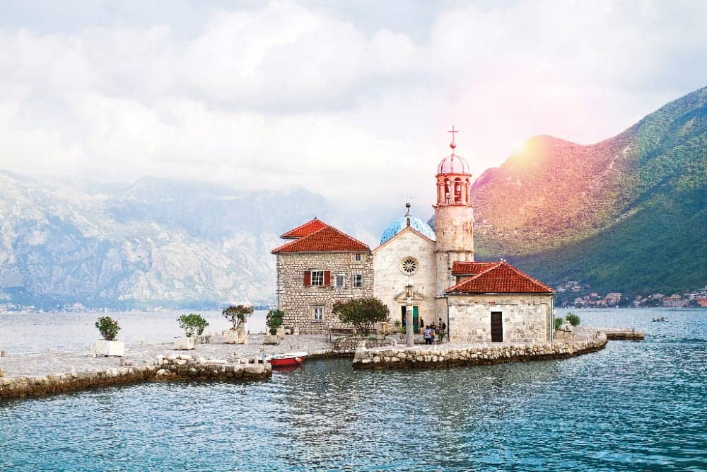 Beautiful scenery with sea and mountains. Fjord in Adriatic Sea. Our Lady of the Rock island and Church in Perast on shore of Boka Kotor bay, Montenegro
