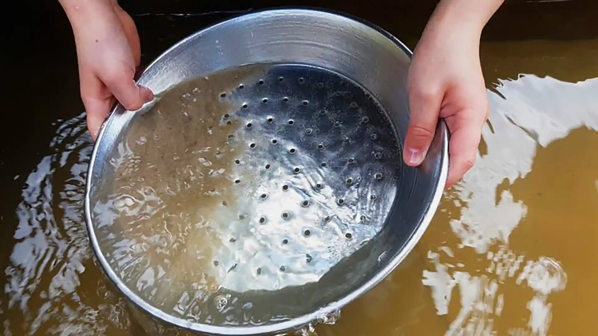 Panning for Gold Hands holding silver pan while panning for gold.