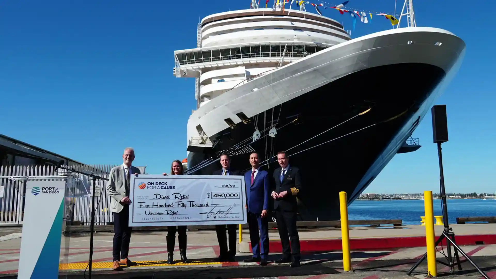 On Deck for a Cause Ukraine Relief Check Presentation View of check donation presentation from On Deck for a Cause program with Holland America Line ship in background.