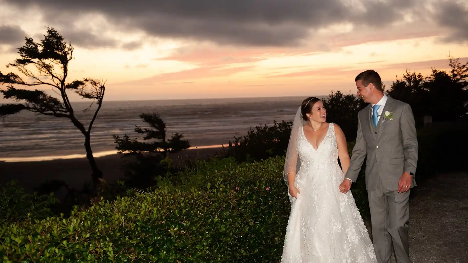 View of couple walking near beach on wedding day during sunset.