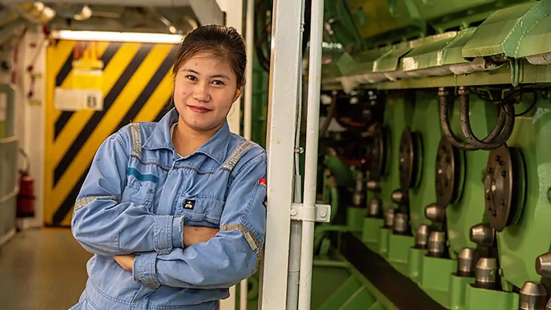 Holland America Line machinist standing near cruise ship engineering equipment.