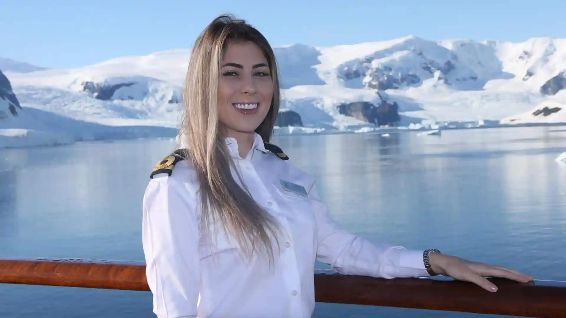 Holland America Line crew officer on deck with glacier in background.