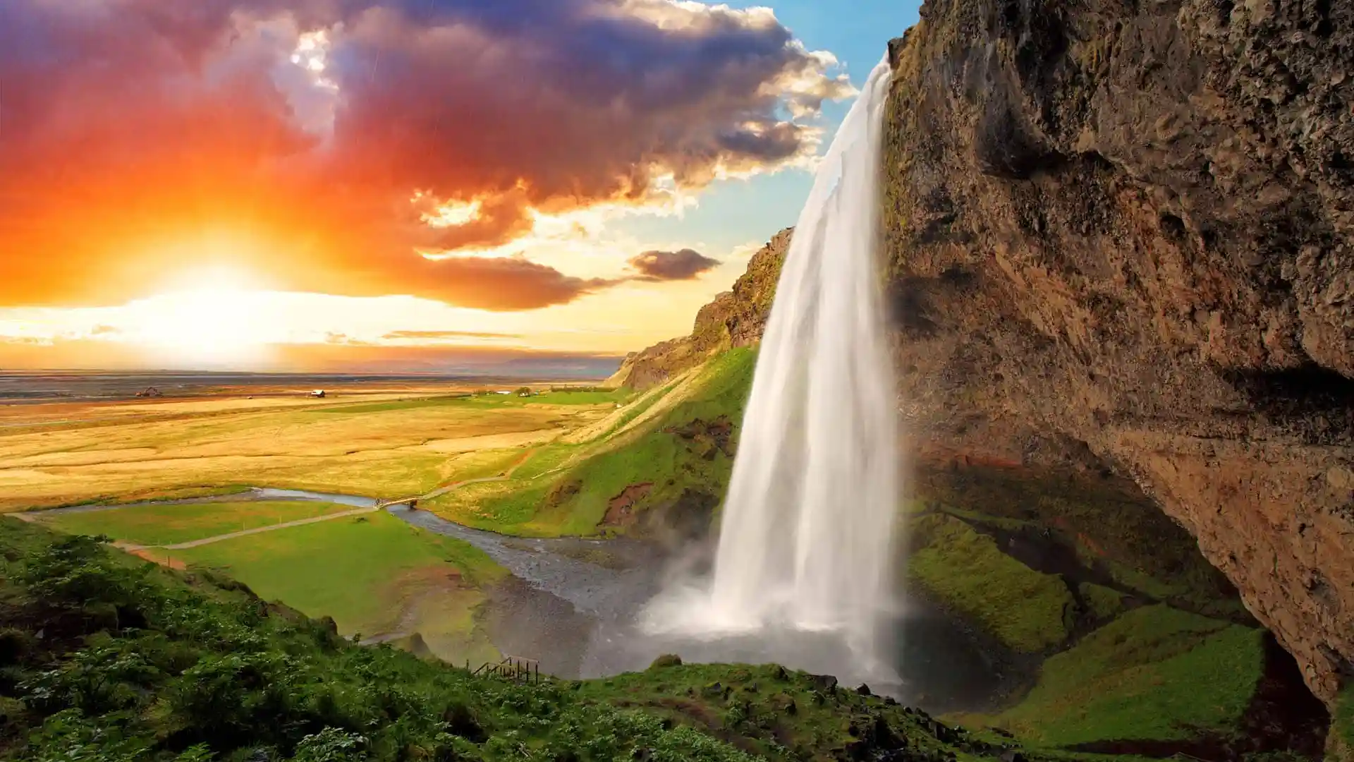 Iceland waterfall during sunrise or sunset accenting the lush landscape.