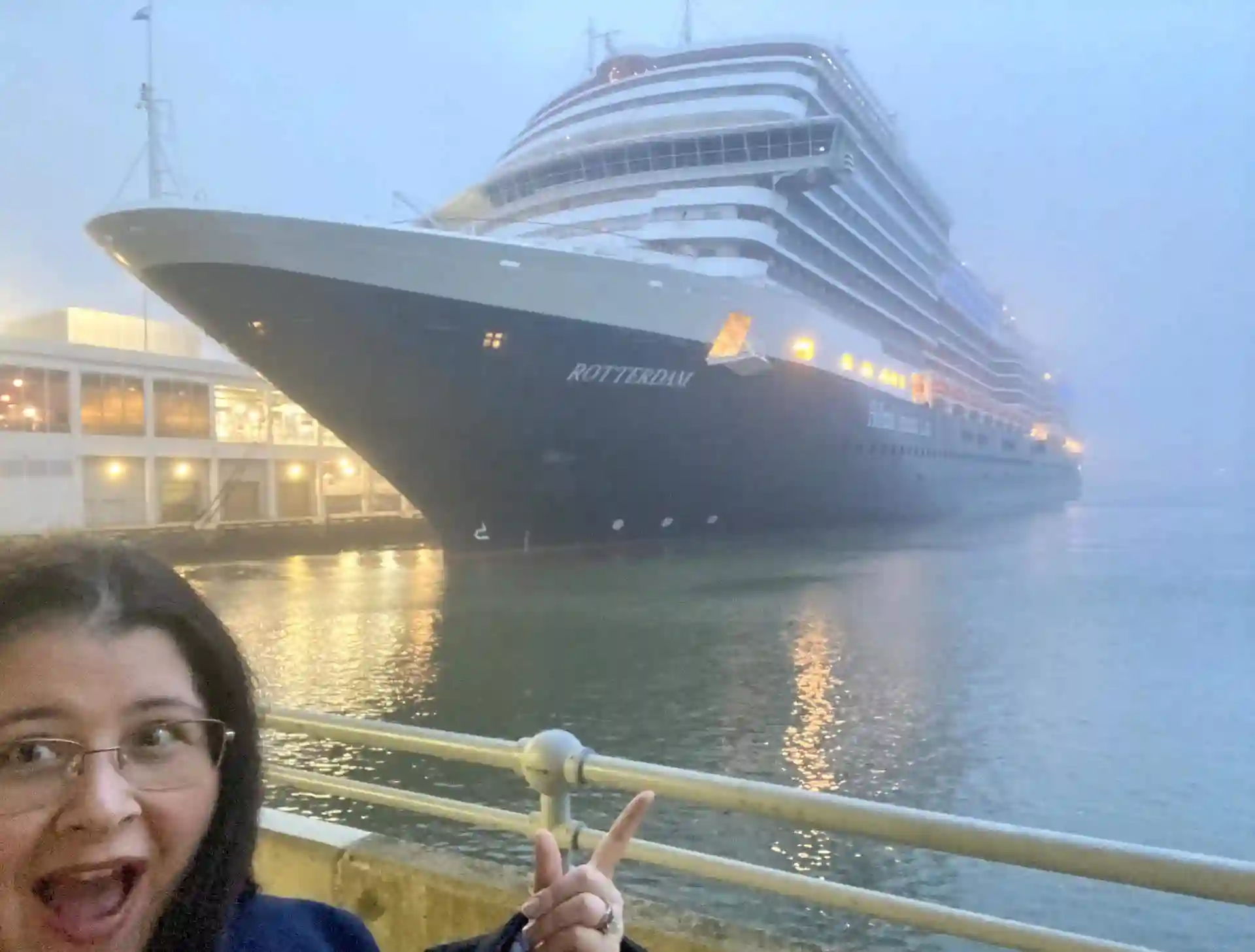 View of person showing excitement, pointing at Holland America Line cruise ship in port.