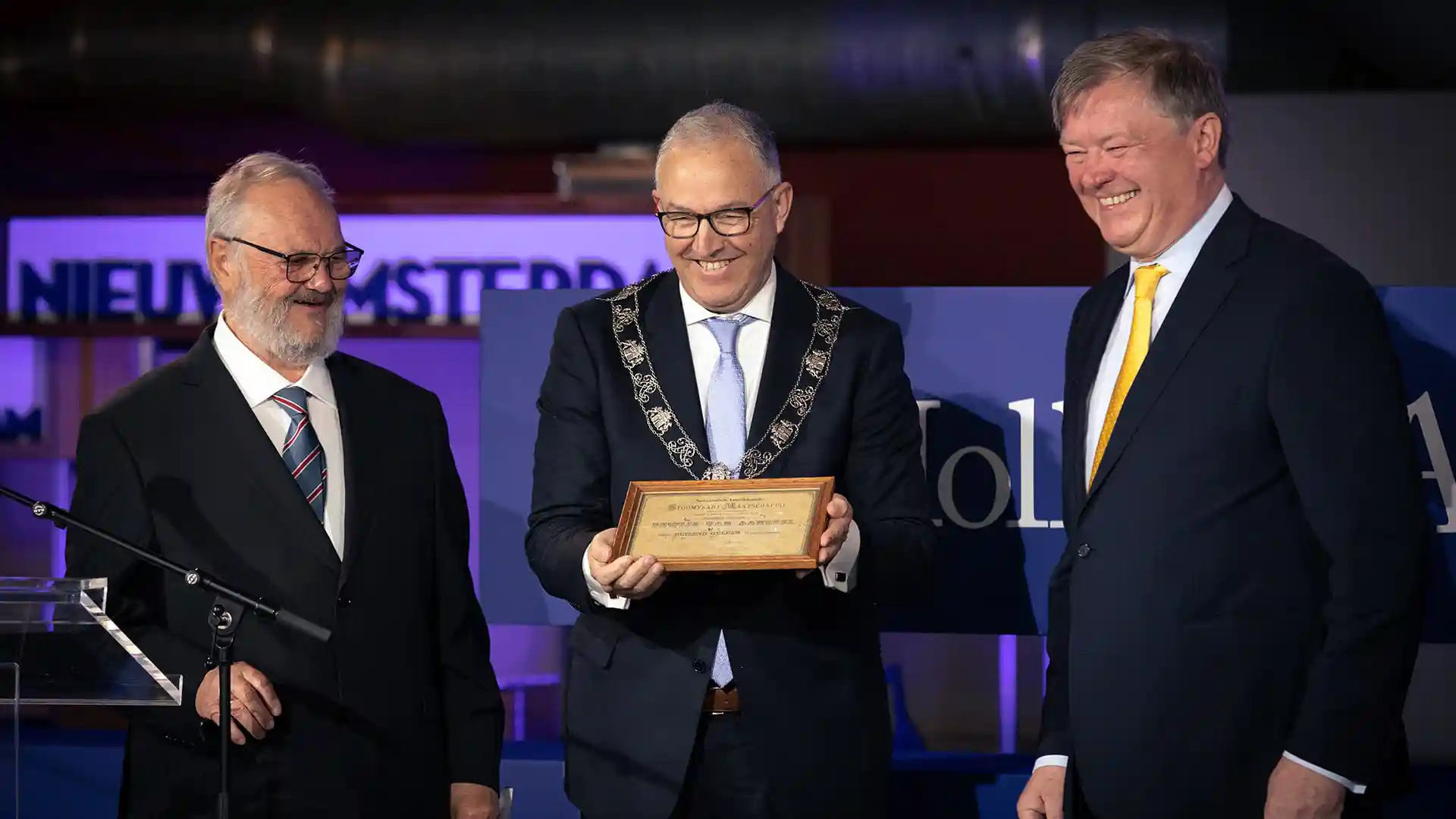 People smiling and holding framed certificate at ceremony celebrating Holland America Line's 150th anniversary.