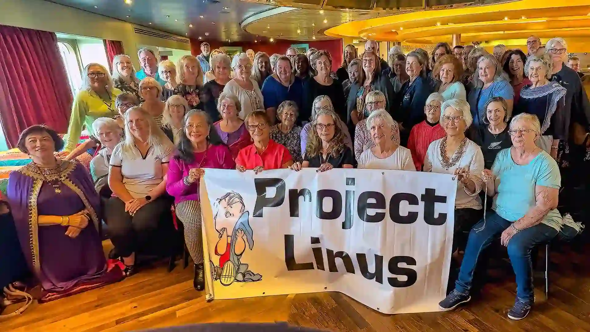 View of people on Holland America Line cruise ship holding Project Linus banner.