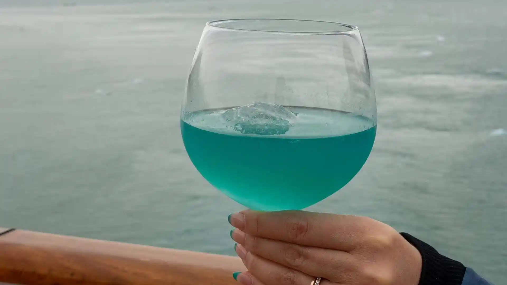 View of Holland America Line cocktail with Alaska glacial water in background.