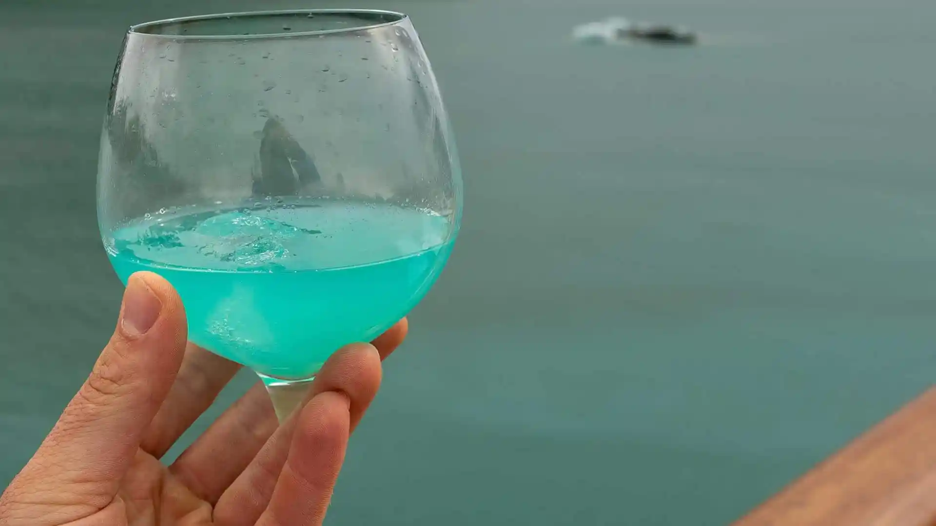 View of Holland America Line cocktail with Alaska glacial water in background.