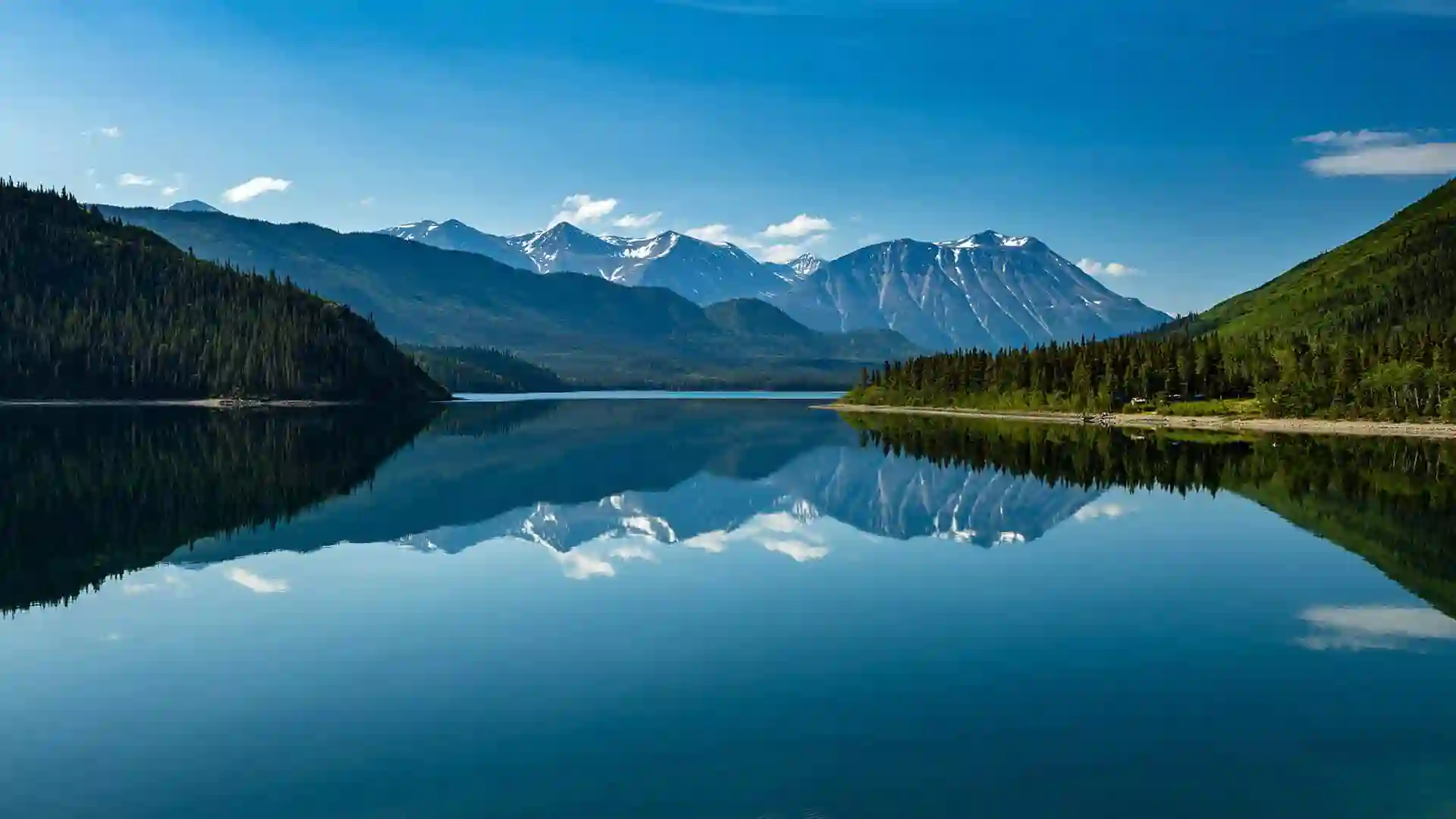 View of calm lake surrounded by lush and mountainous landscape in Canada.