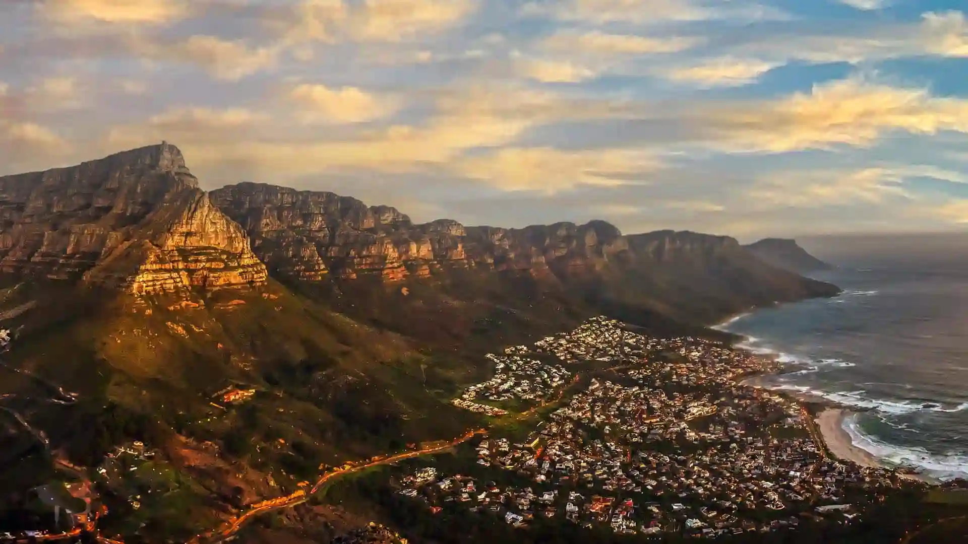 Aerial view of Cape Town, South Africa, where the sea meets the shore, during sunset.