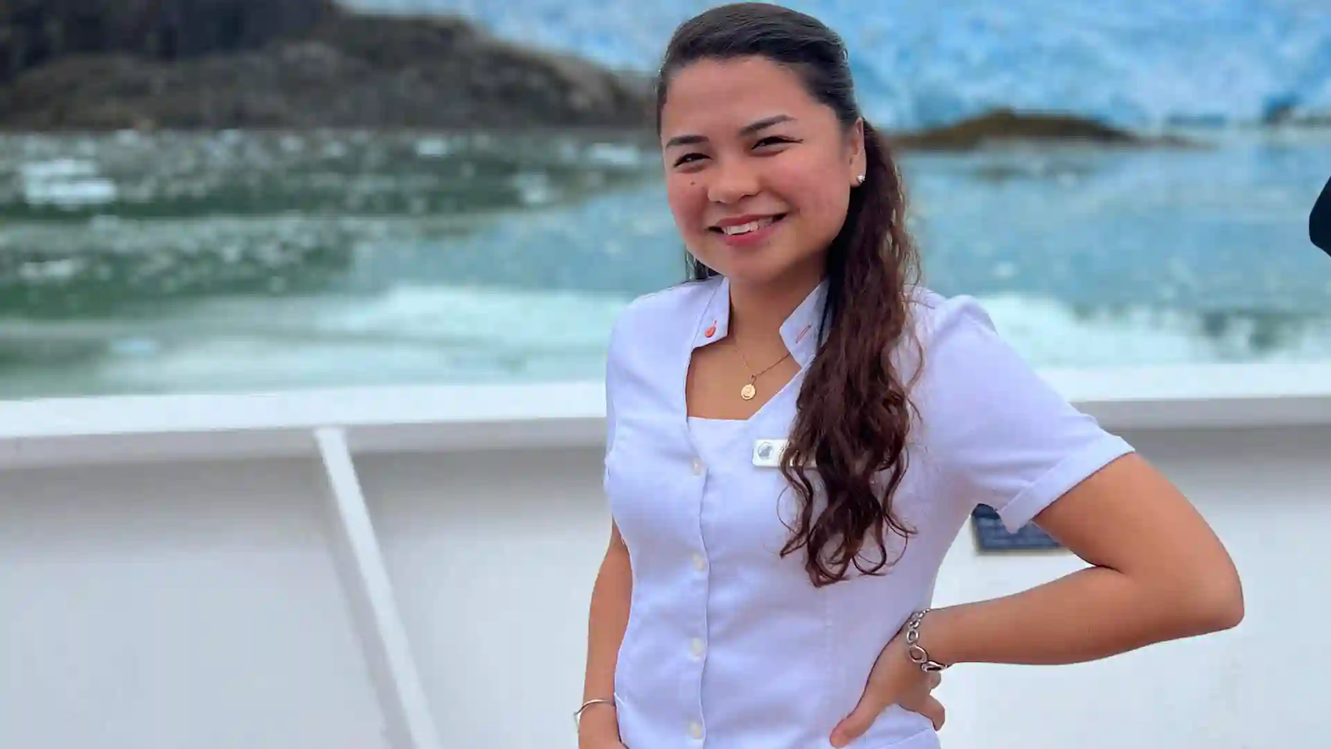 Holland America Line Lounge Concierge Holland America Line crew member on deck with glacier in background.