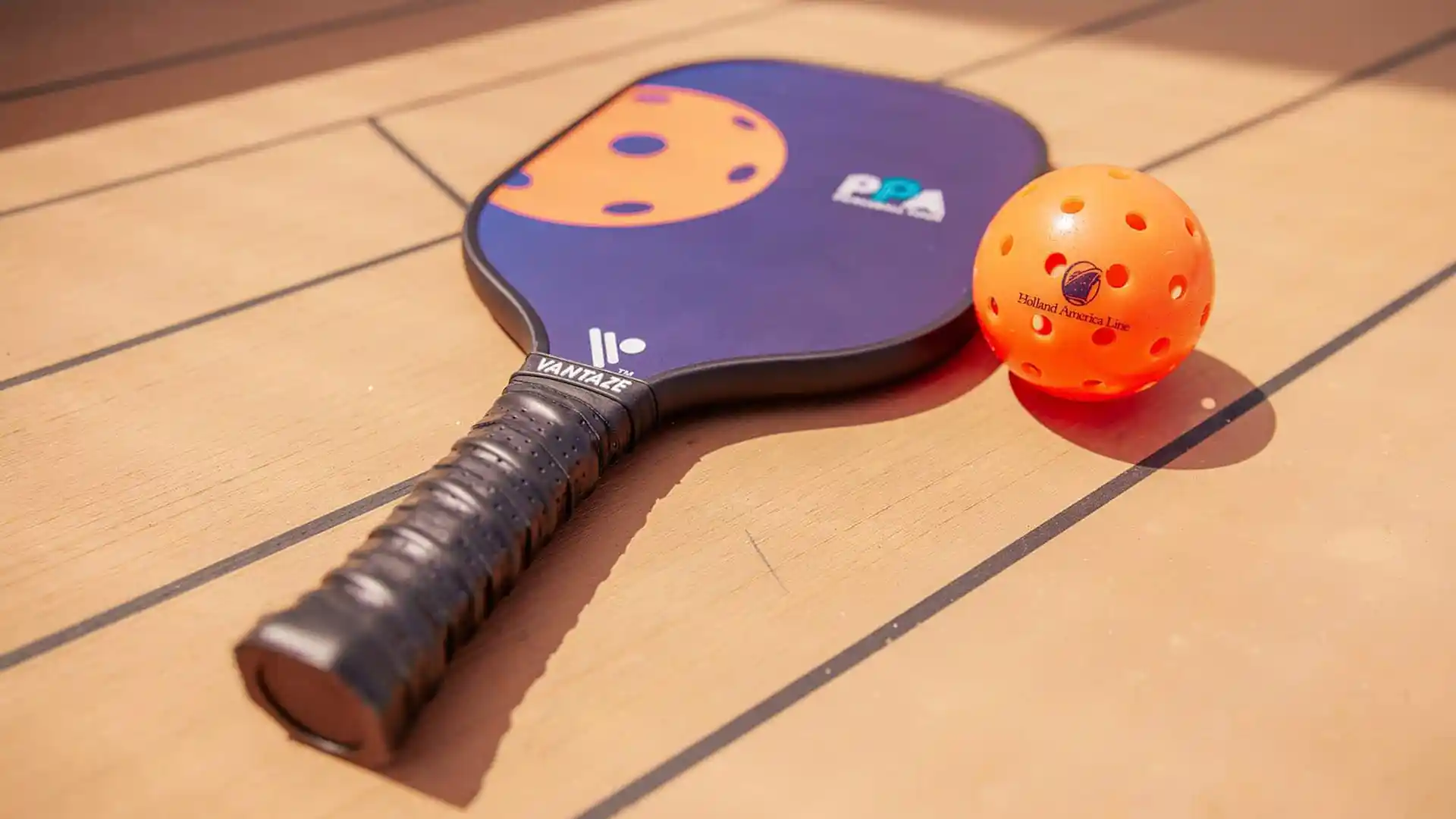Holland America Line Pickleball View of pickleball paddle and ball on Holland America Line cruise deck.