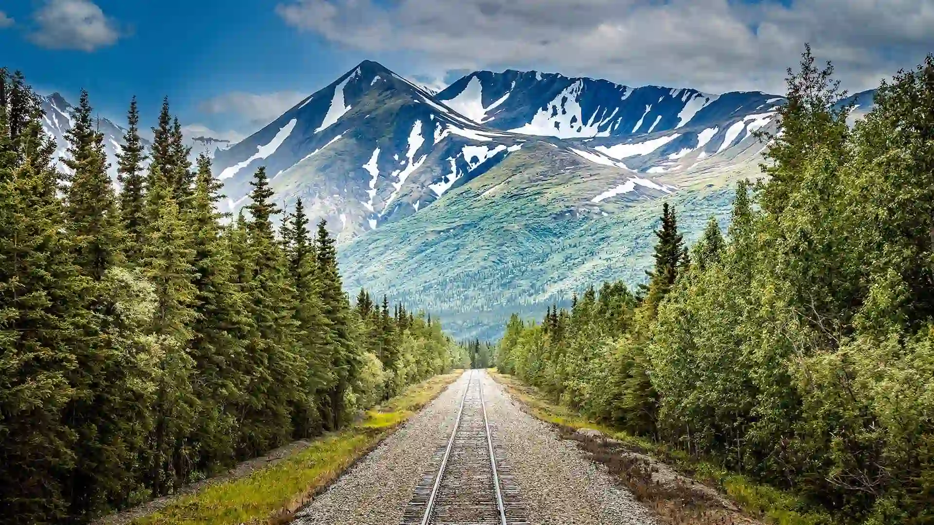 View of train tracks surrounded by mountainous landscape.