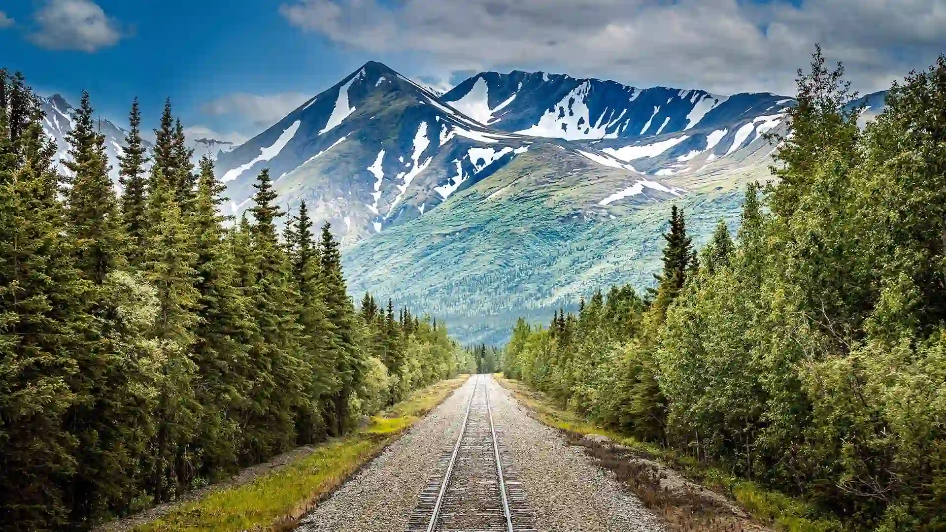 Railroad in Alaska View of train tracks surrounded by mountainous landscape.