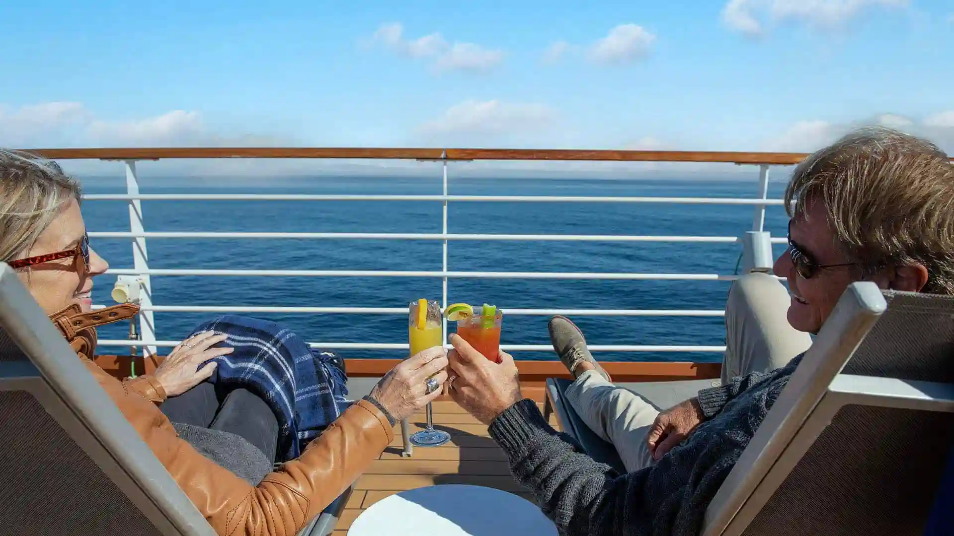 Two people on cruise deck with cocktails.