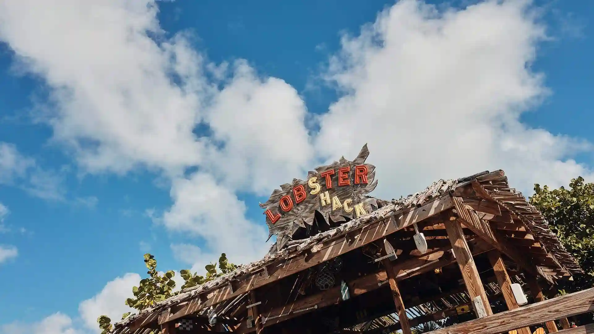 View of Lobster Shack sign beneath partly cloudy sky in Half Moon Cay, Bahamas.
