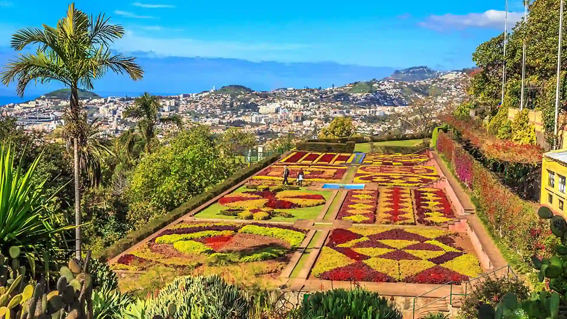 View of multicolored botanical gardens in Portugal surrounded by a green lush landscape.