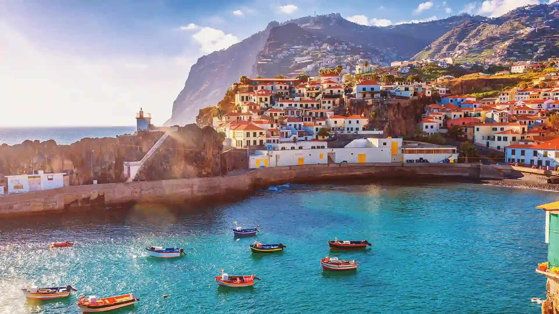 Boats floating on bright blue water in harbor near hillside village.