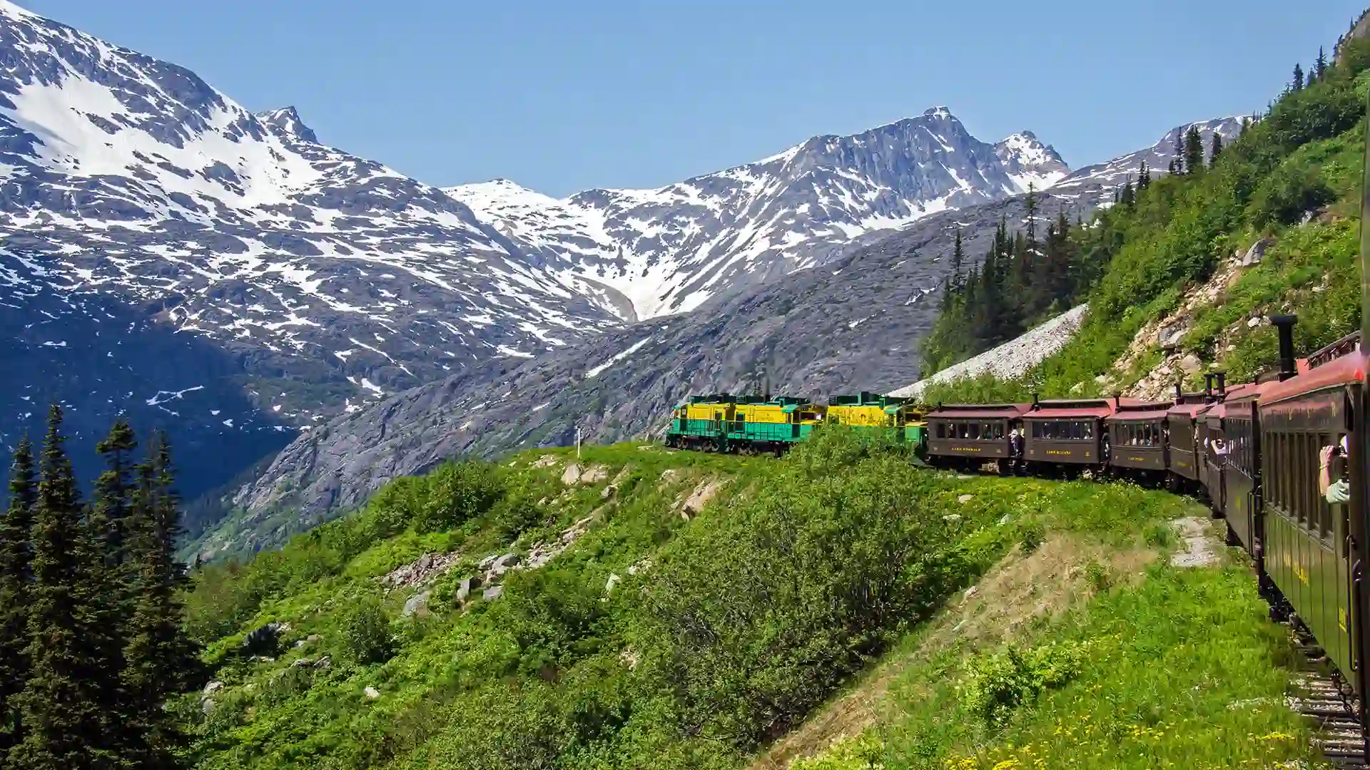 View of train through rocky and lush landscape.