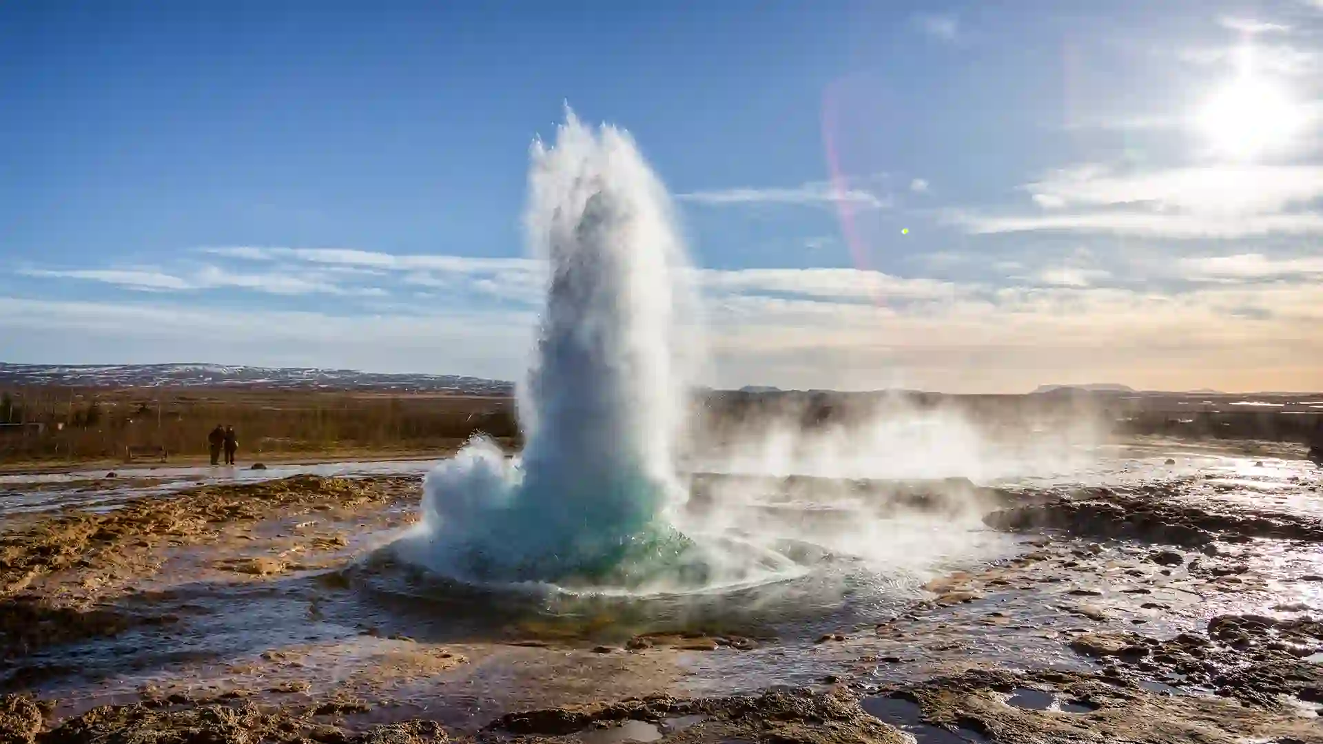 View of geyser spraying upward from rocky ground.