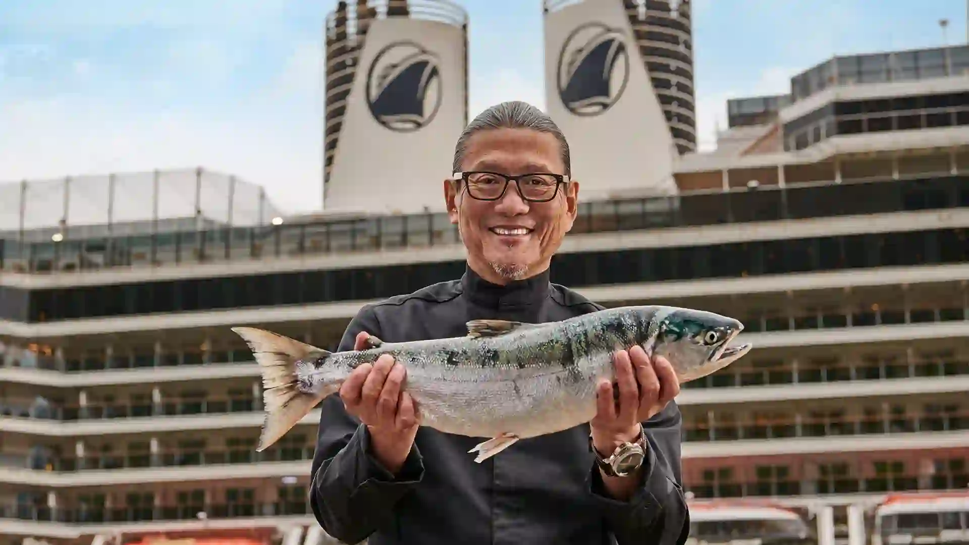 Person holding fish in front of cruise ship.