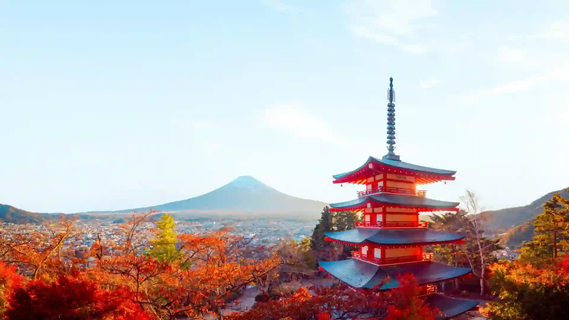 Japan View of temple and orange and red fall foliage with mountain in the background.