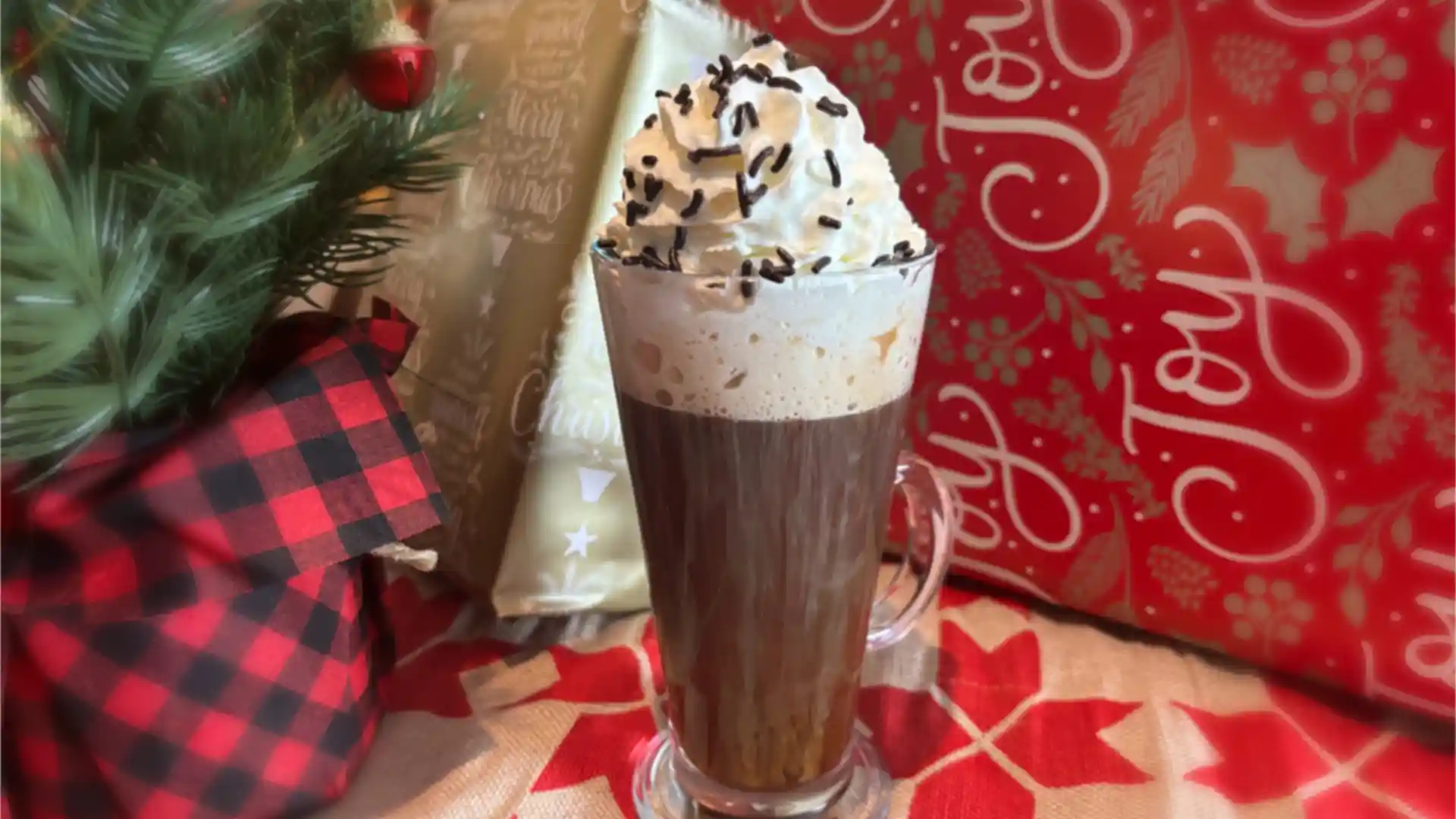 Holiday coffee cocktail with Kahlua and other ingredients, topped with whipped cream and chocolate sprinkles in mug.