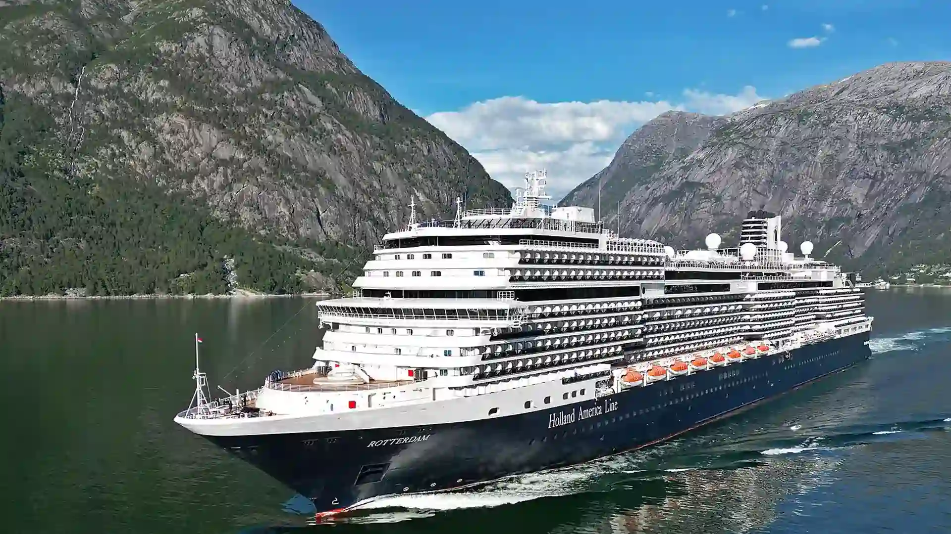 View of Holland America Line cruise ship sailing around fjords.