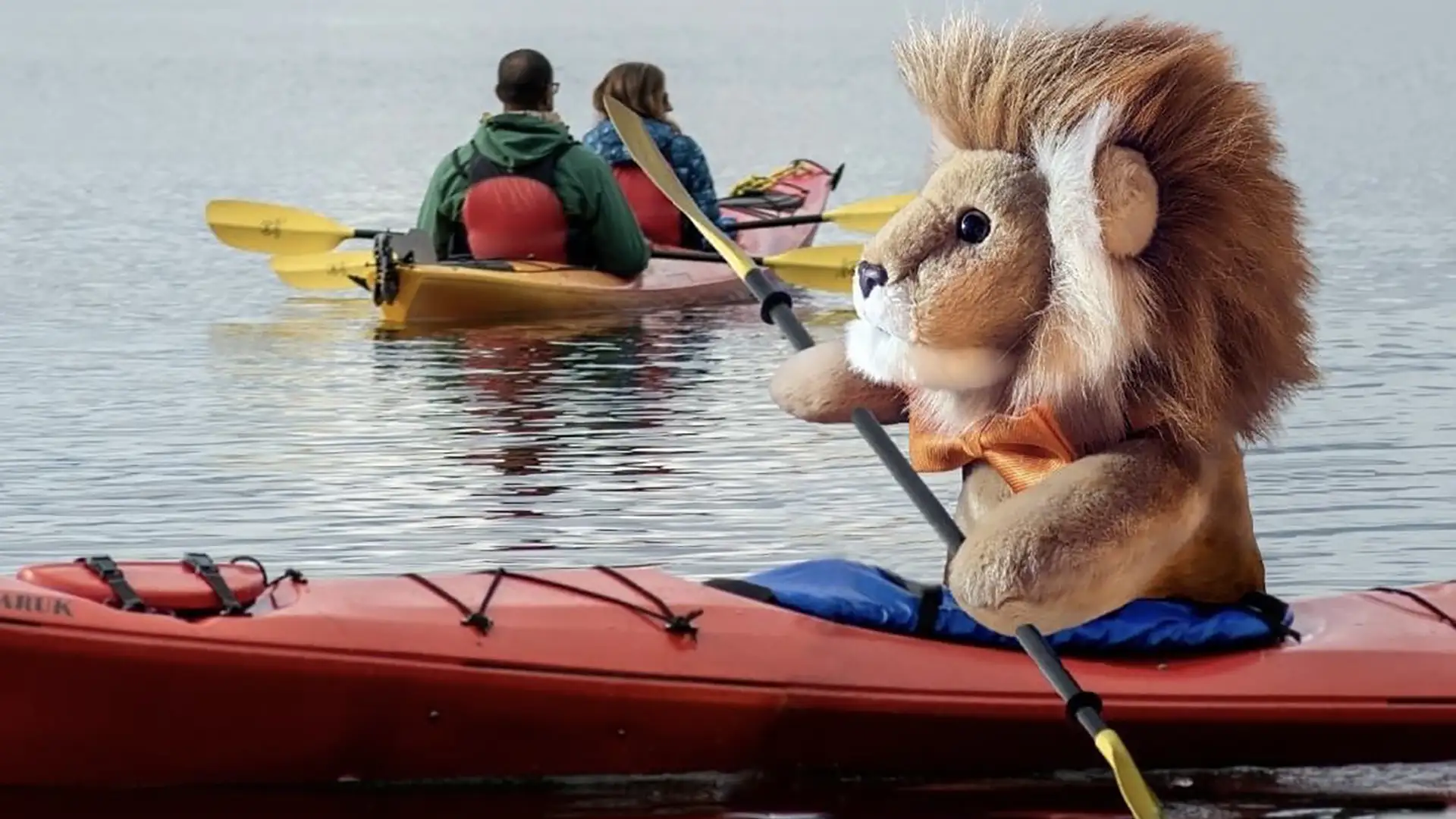 Holland America Line's lion mascot in a red kayak with two kayakers in the background.