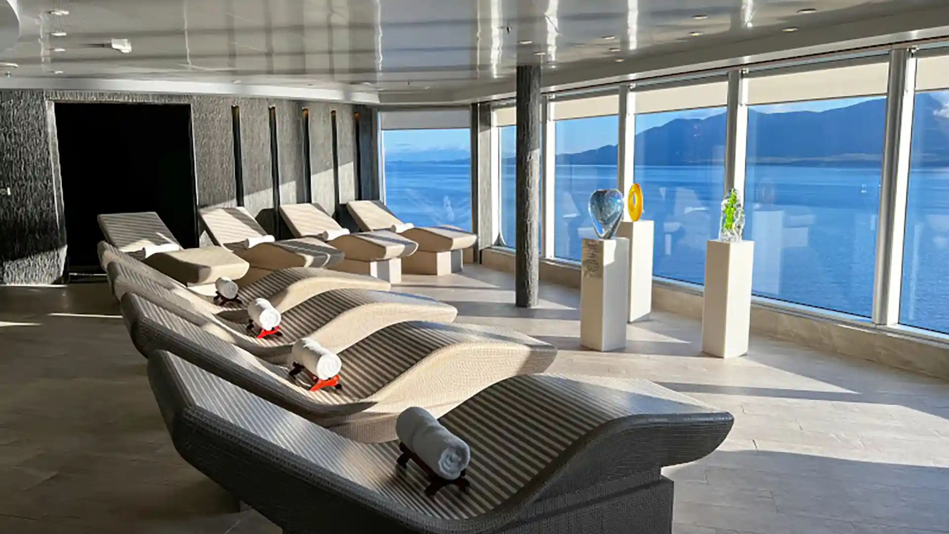 View of loungers with ocean views in thermal suite on Holland America Line ship.