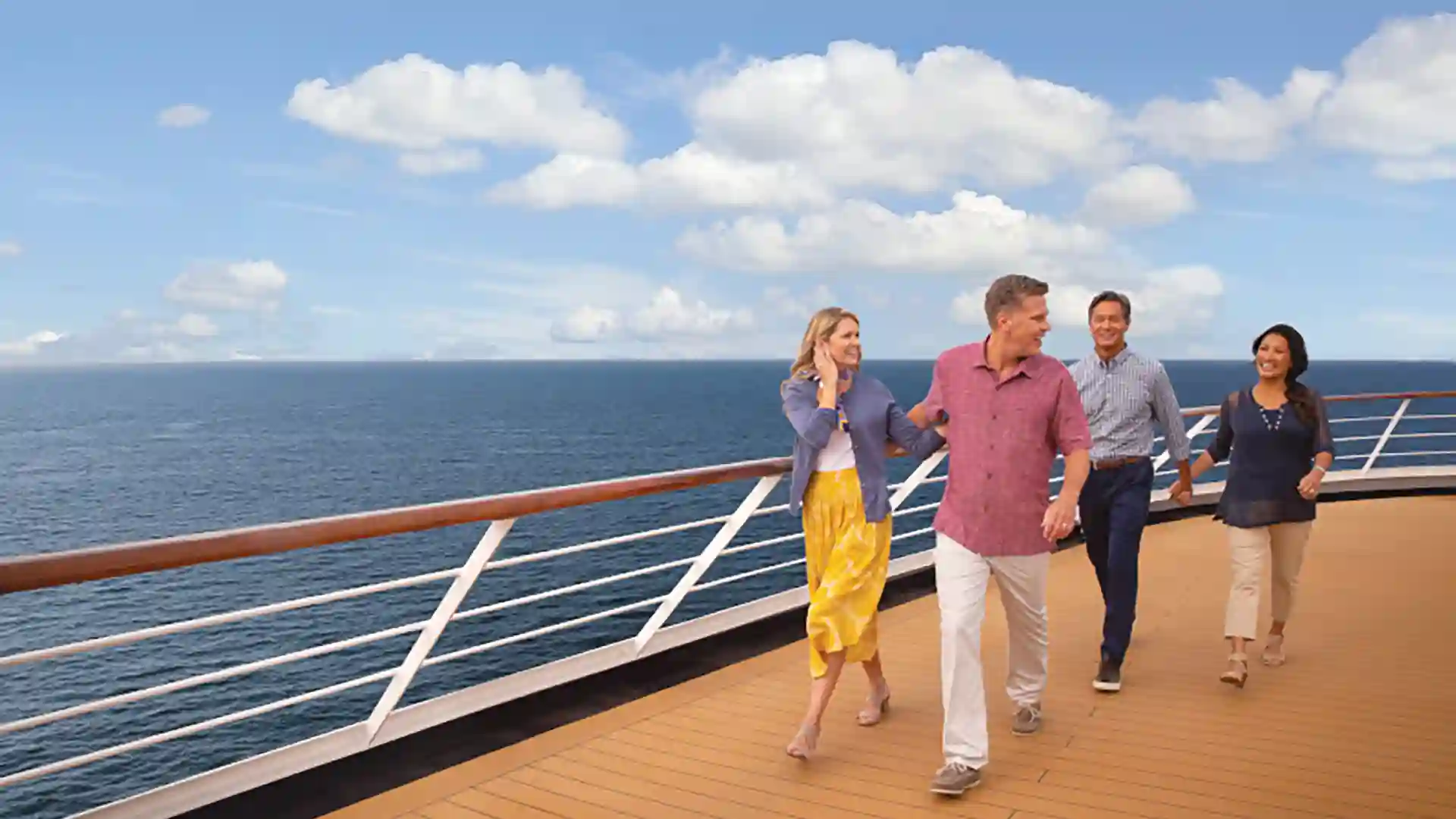 People walking on cruise ship deck with ocean in background.