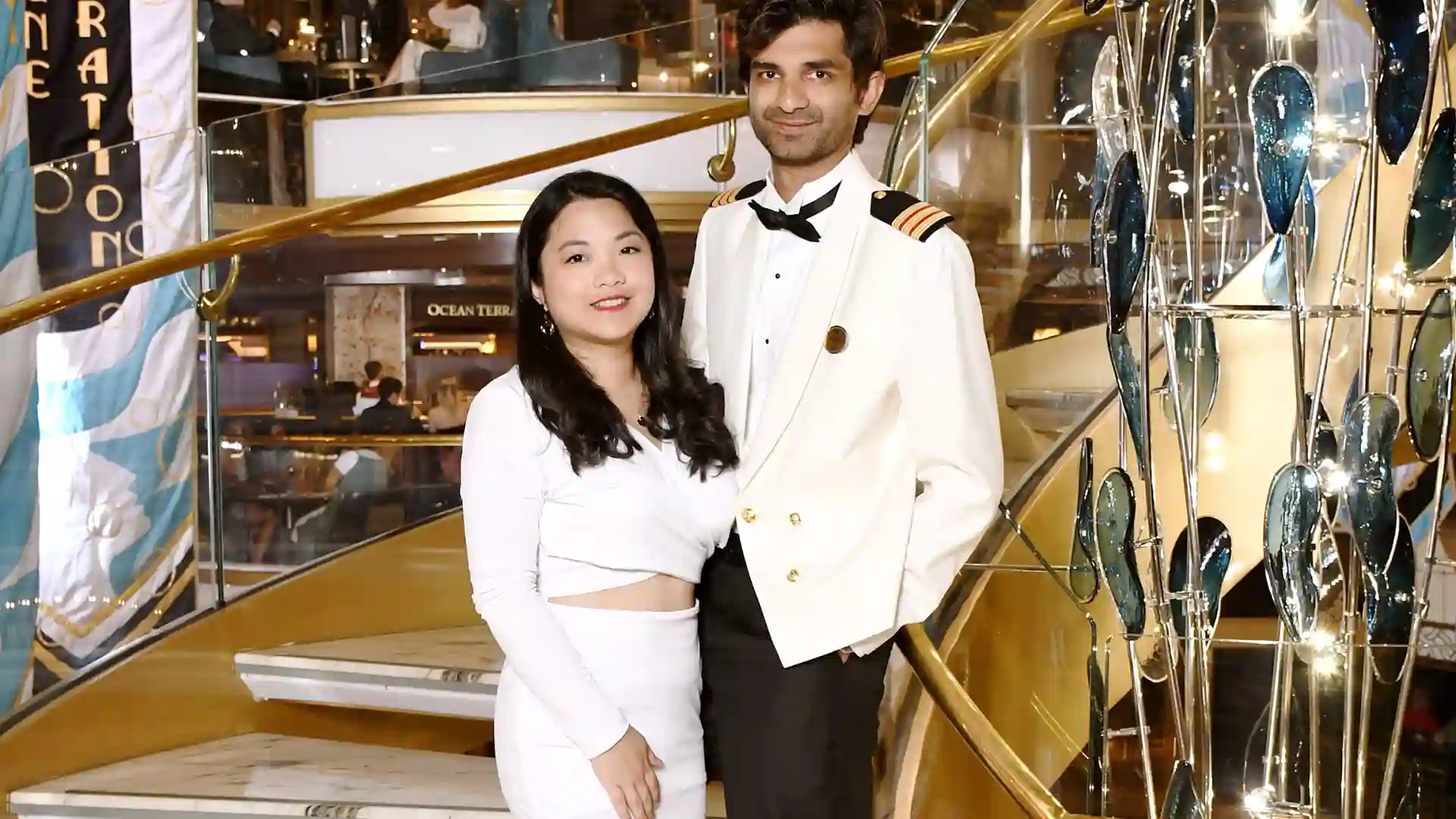 View of couple in white formal attire on Holland America Line cruise, standing on staircase for engagement photo.