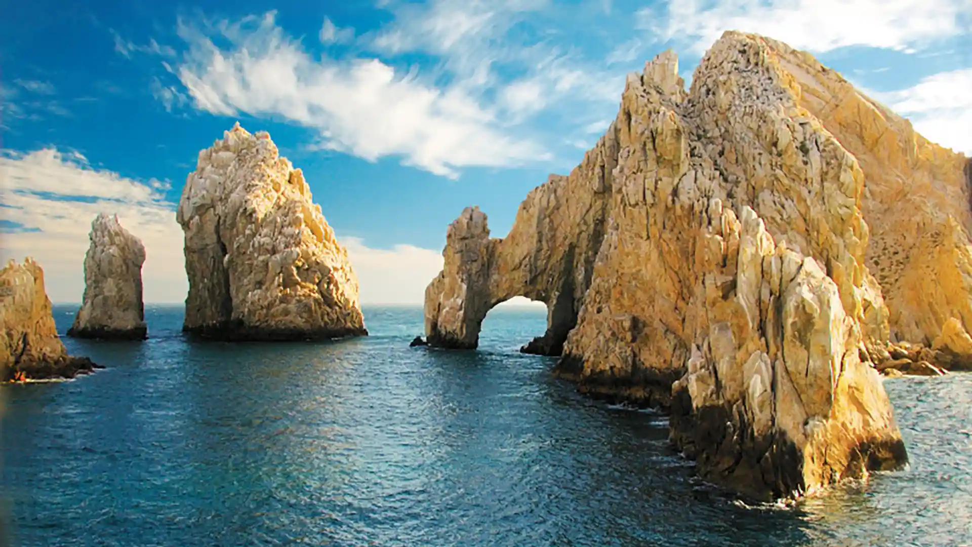 View of towering rock formations in blue waters near shore in Mexico.
