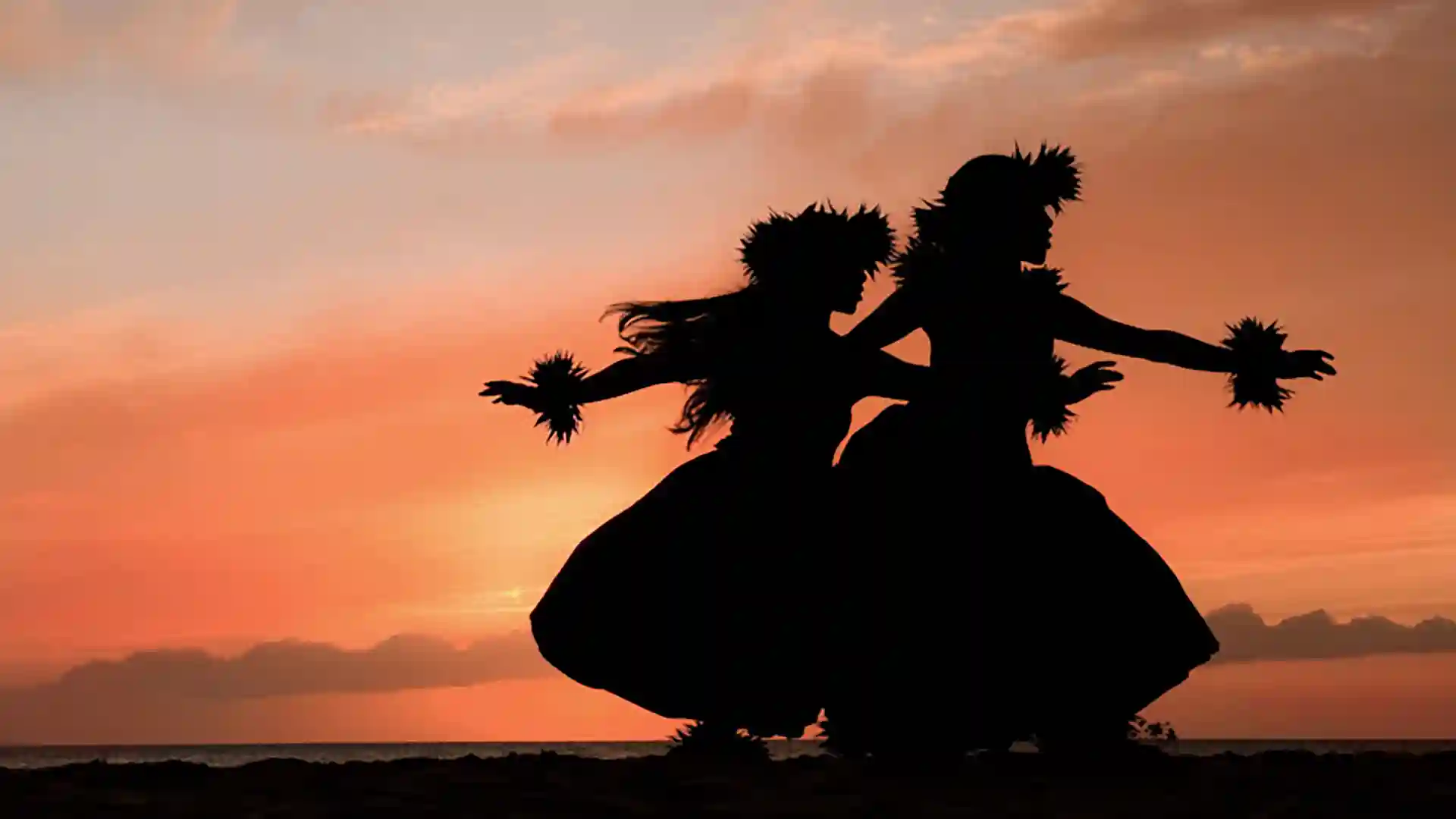 View of hula dancers at sunset on beach in Hawaii.