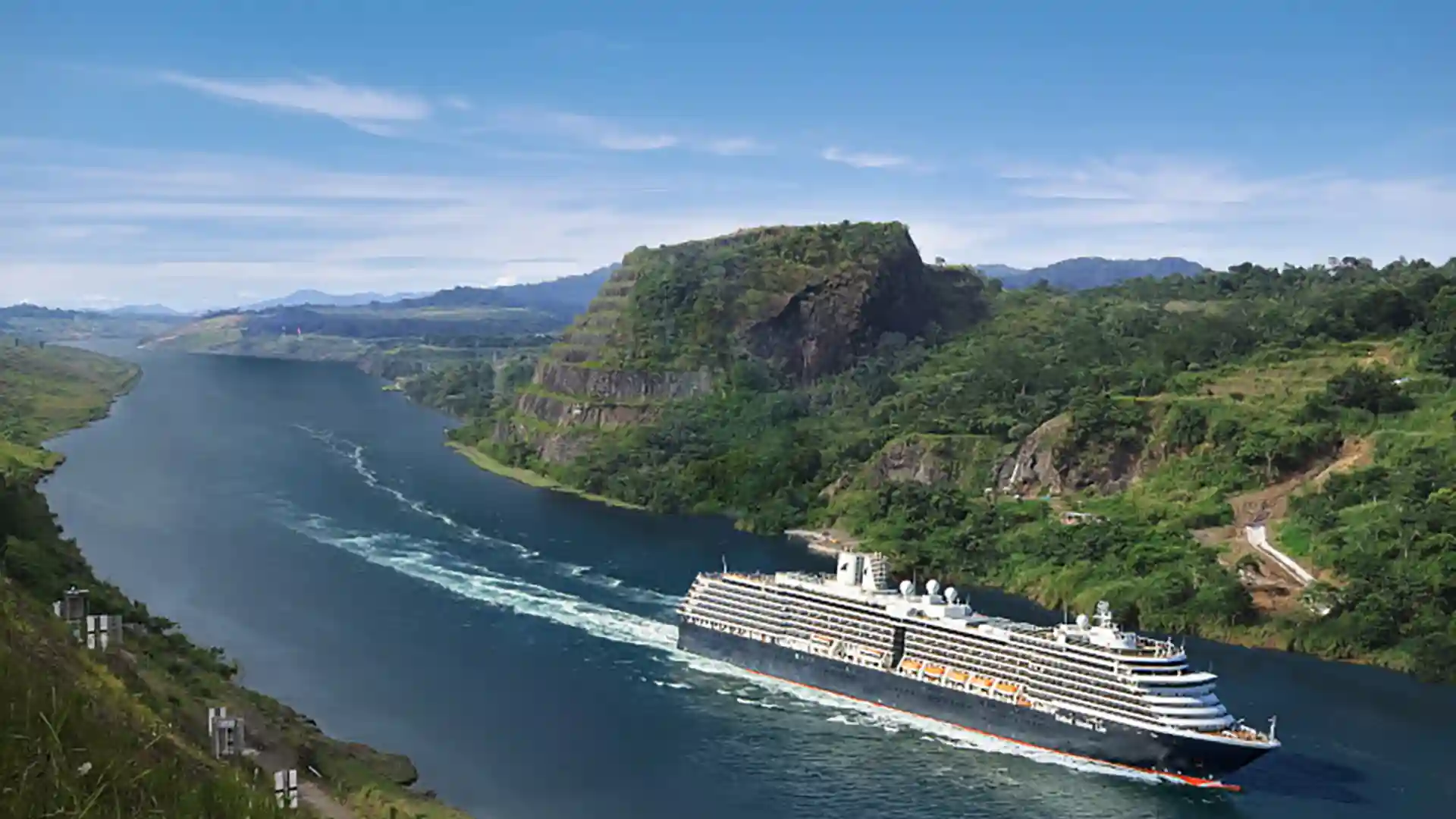 View of Holland America Line cruise ship sailing the Panama Canal, surrounded by lush landscapes.