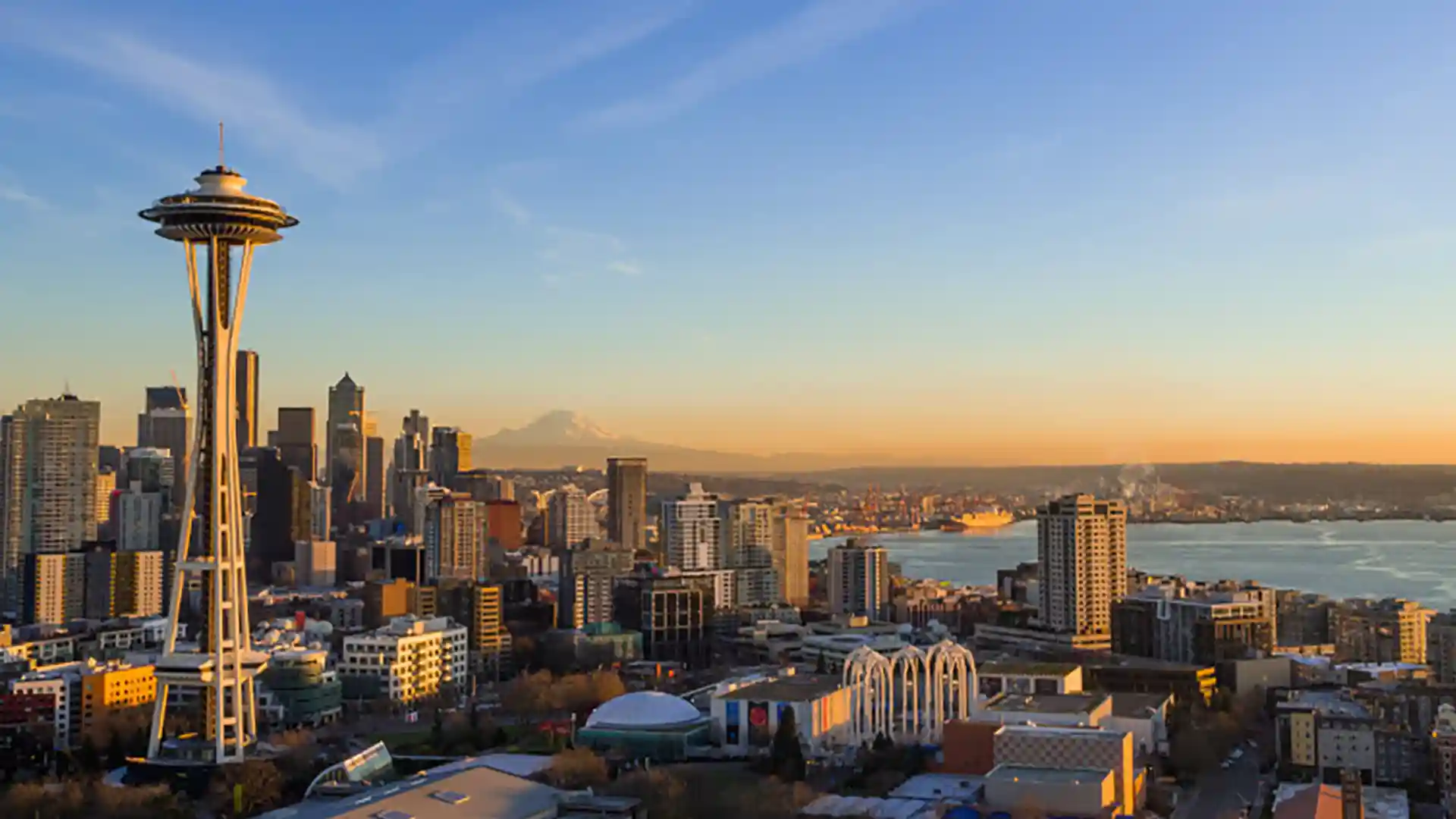 View of Seattle Space Needle and city landscape with Mt. Rainier in background.