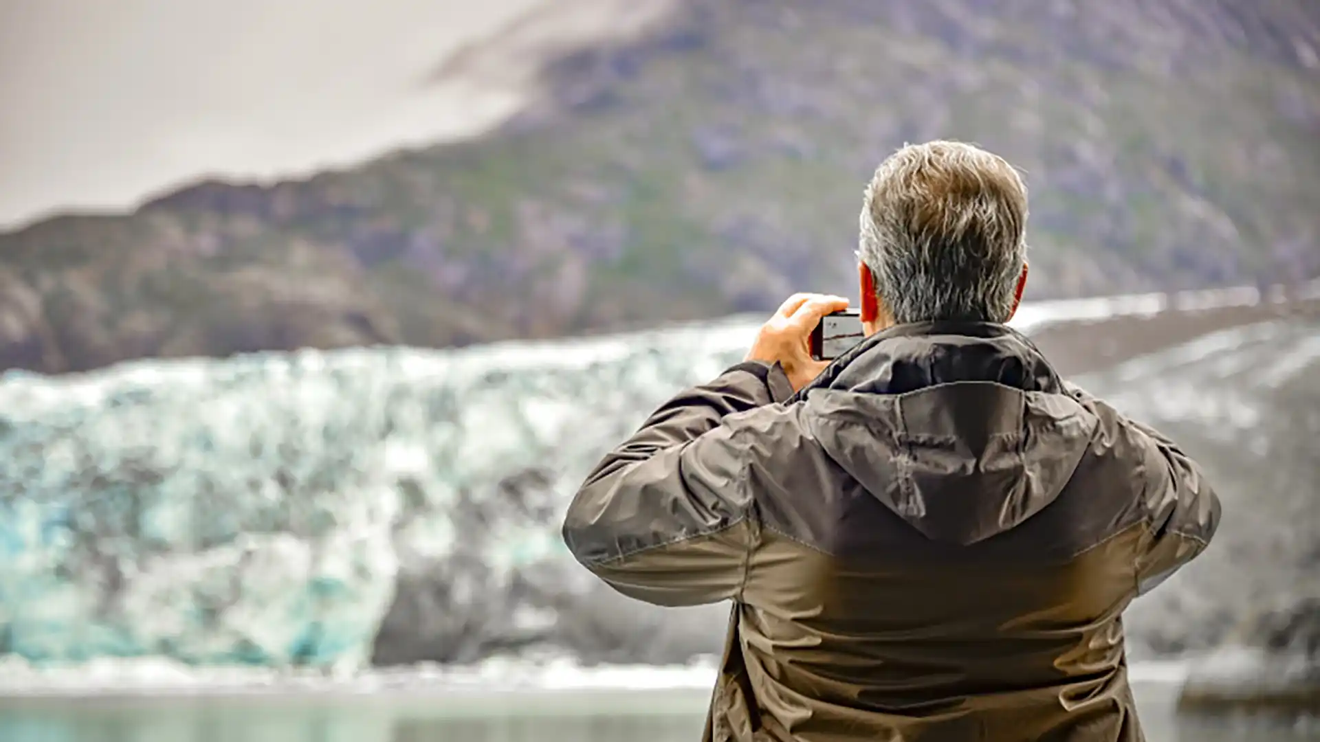 Person using smartphone to take photos of Alaska glaciers.
