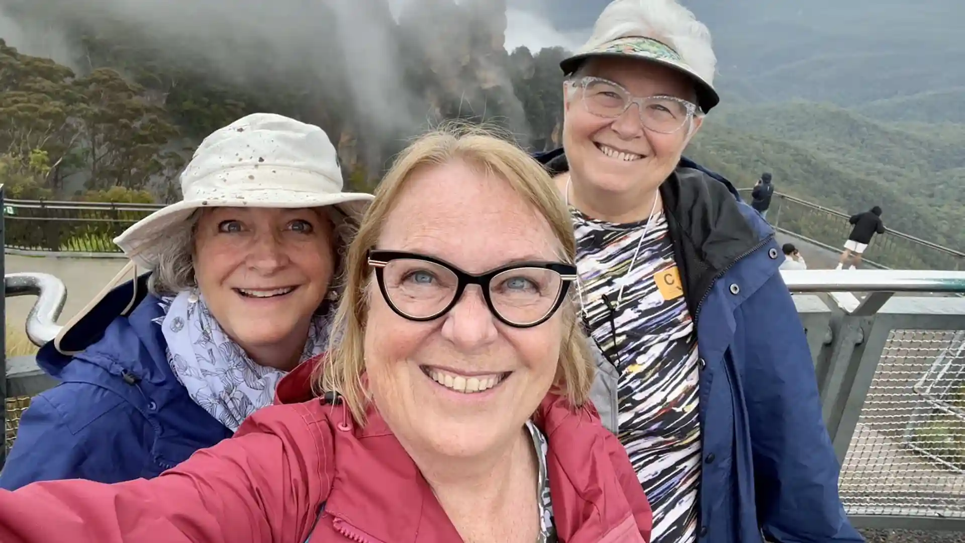 Three sisters taking a group photo near Australia's Blue Mountains during a Grand World Voyage with Holland America Line.