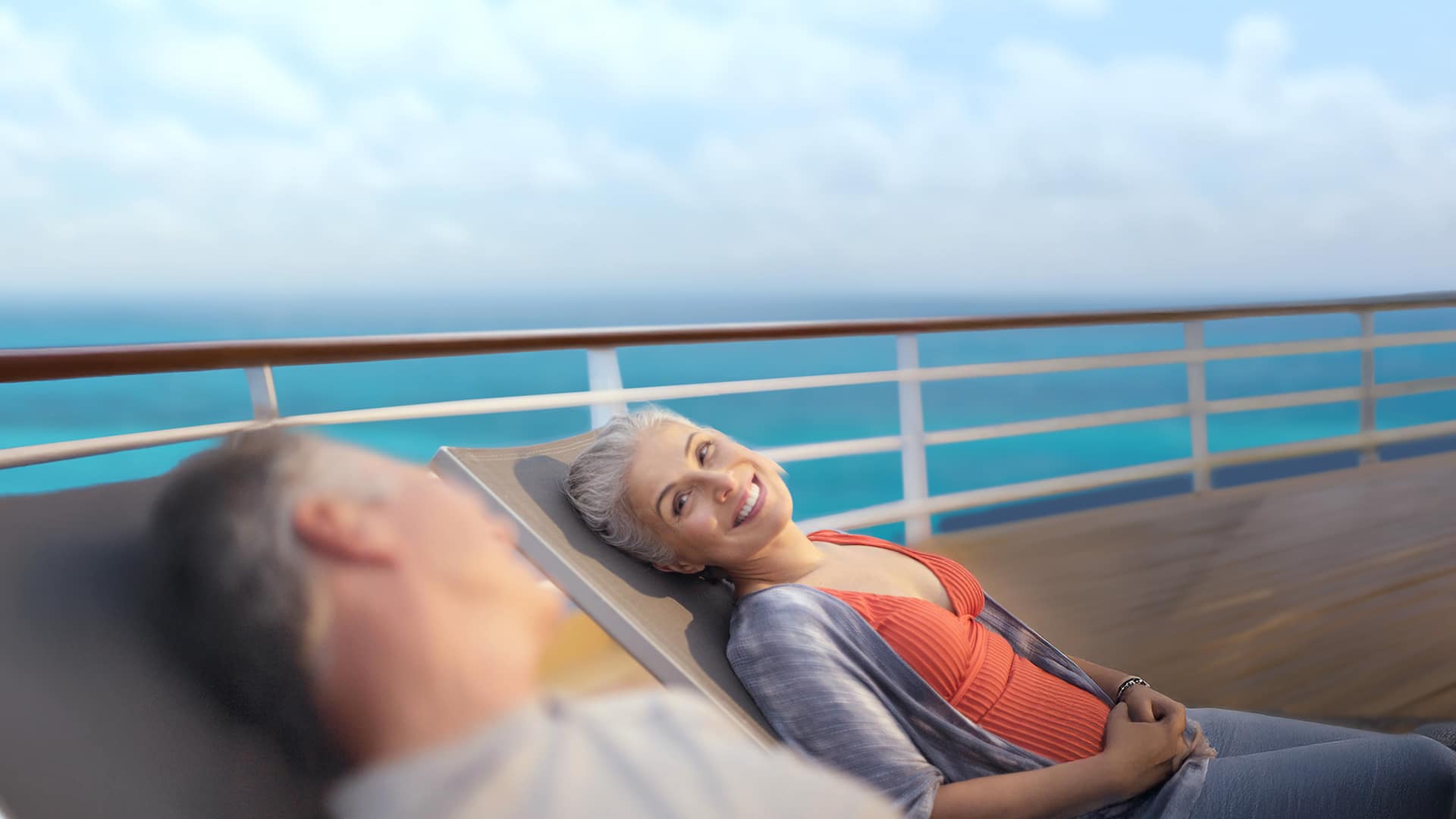 Two adults on the deck of a Holland America cruise ship gazing at each other.