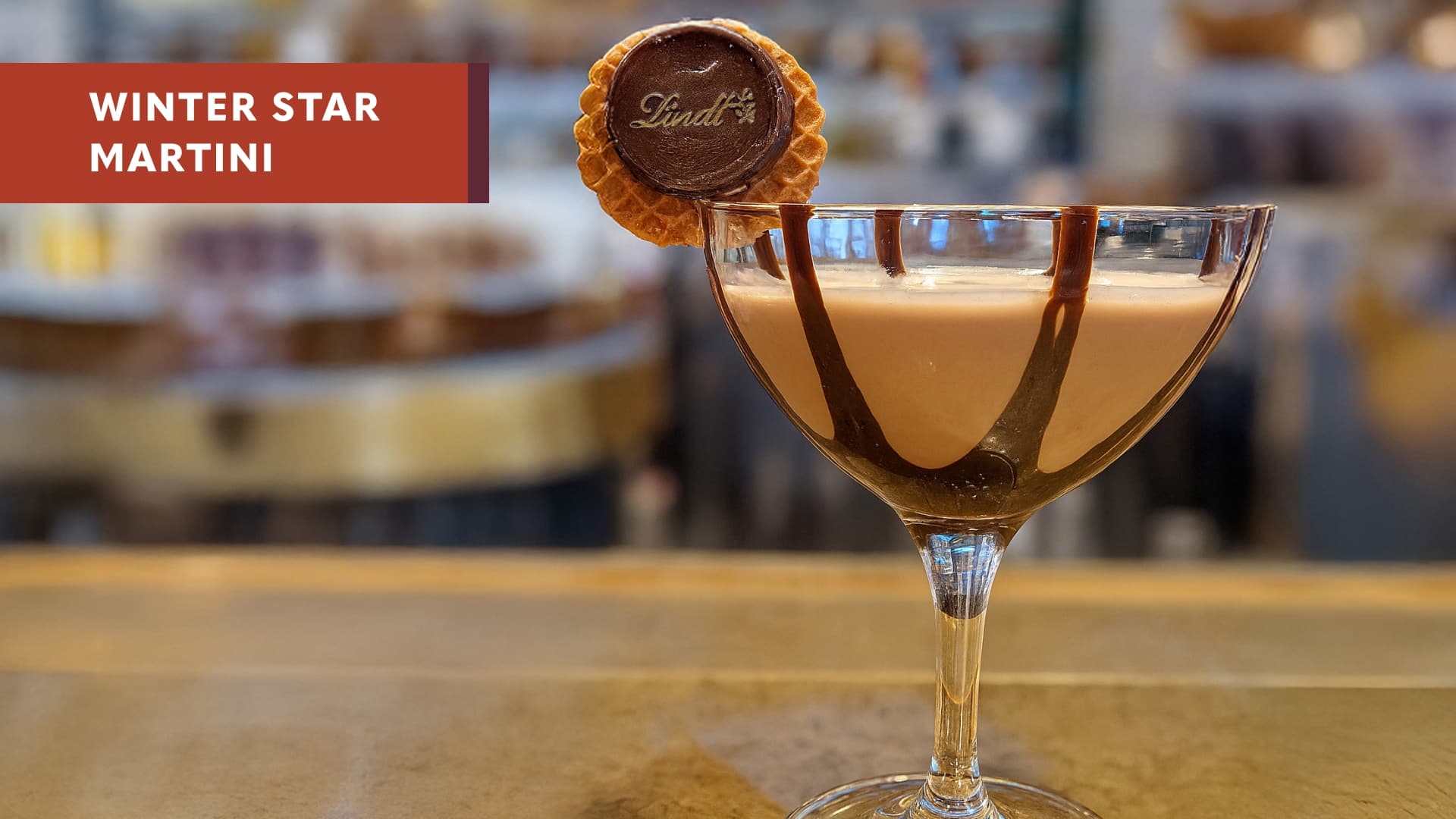 A chocolate and Bailey’s holiday cocktail in a martini glass with chocolate sauce with the text Winter Star Martini.