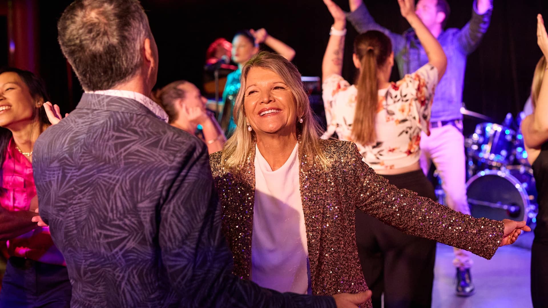 A woman in a gold sparkly jacket on the dance floor.