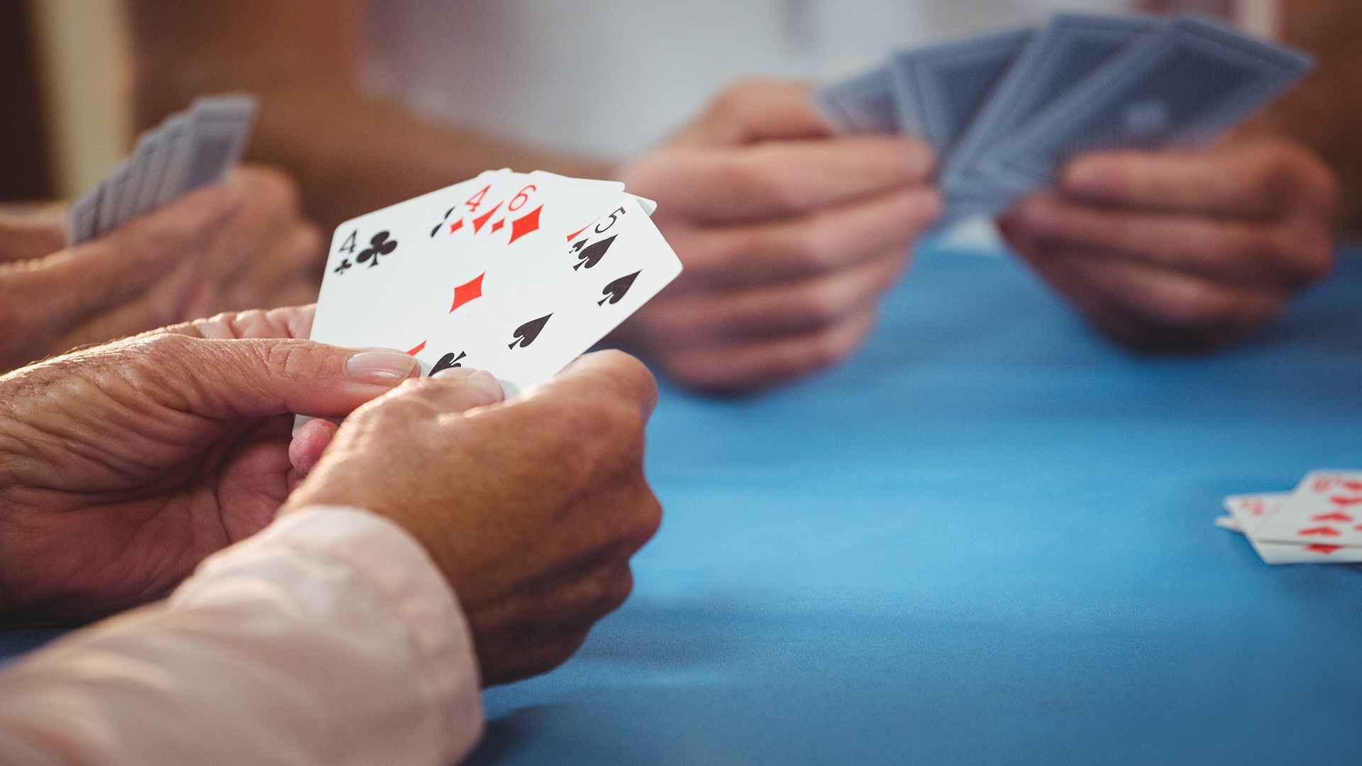 Four players in a card game with one hand showing.