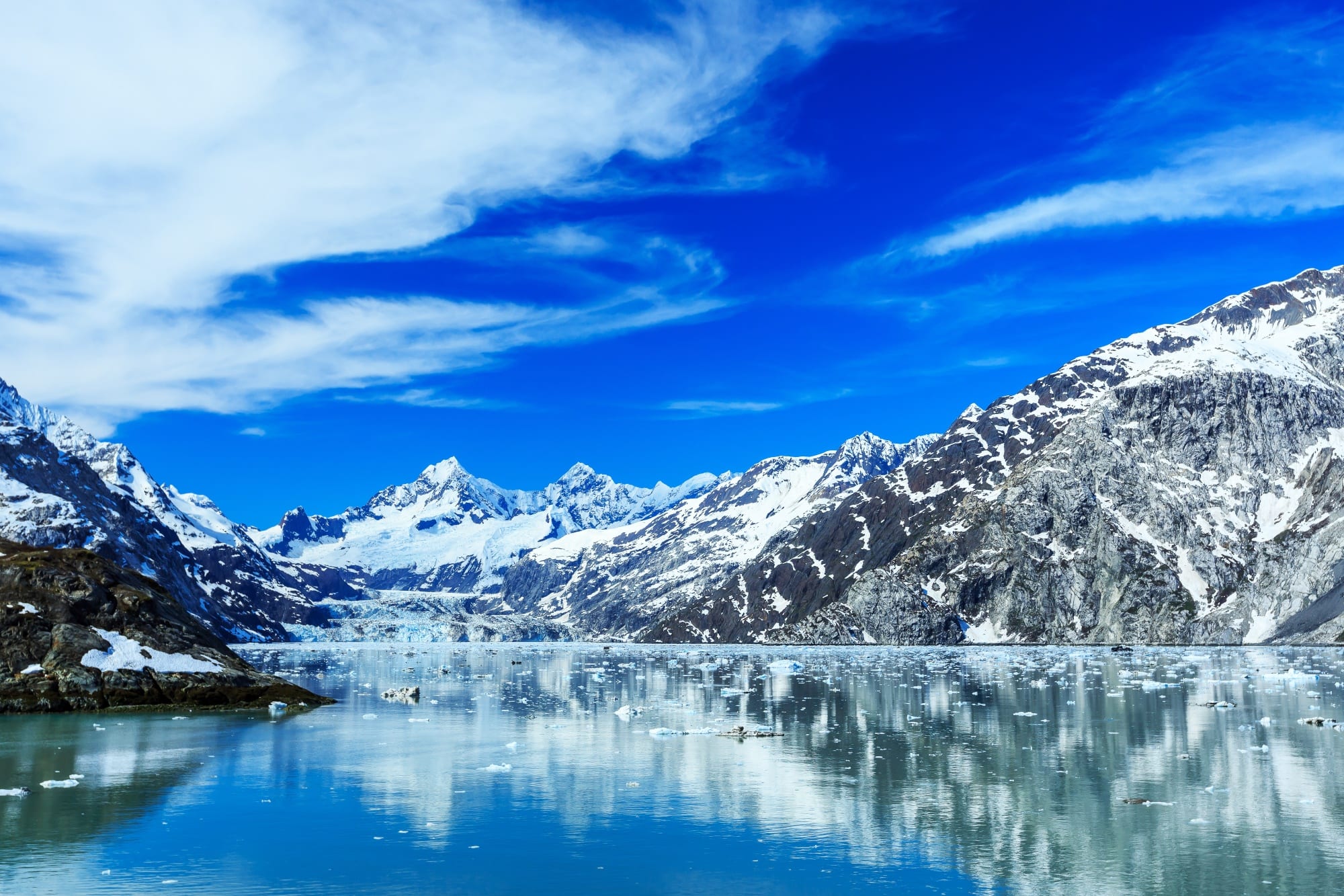 Glacier Bay National Park & Preserve pictured with snow-capped mountains reflected in pristine water.