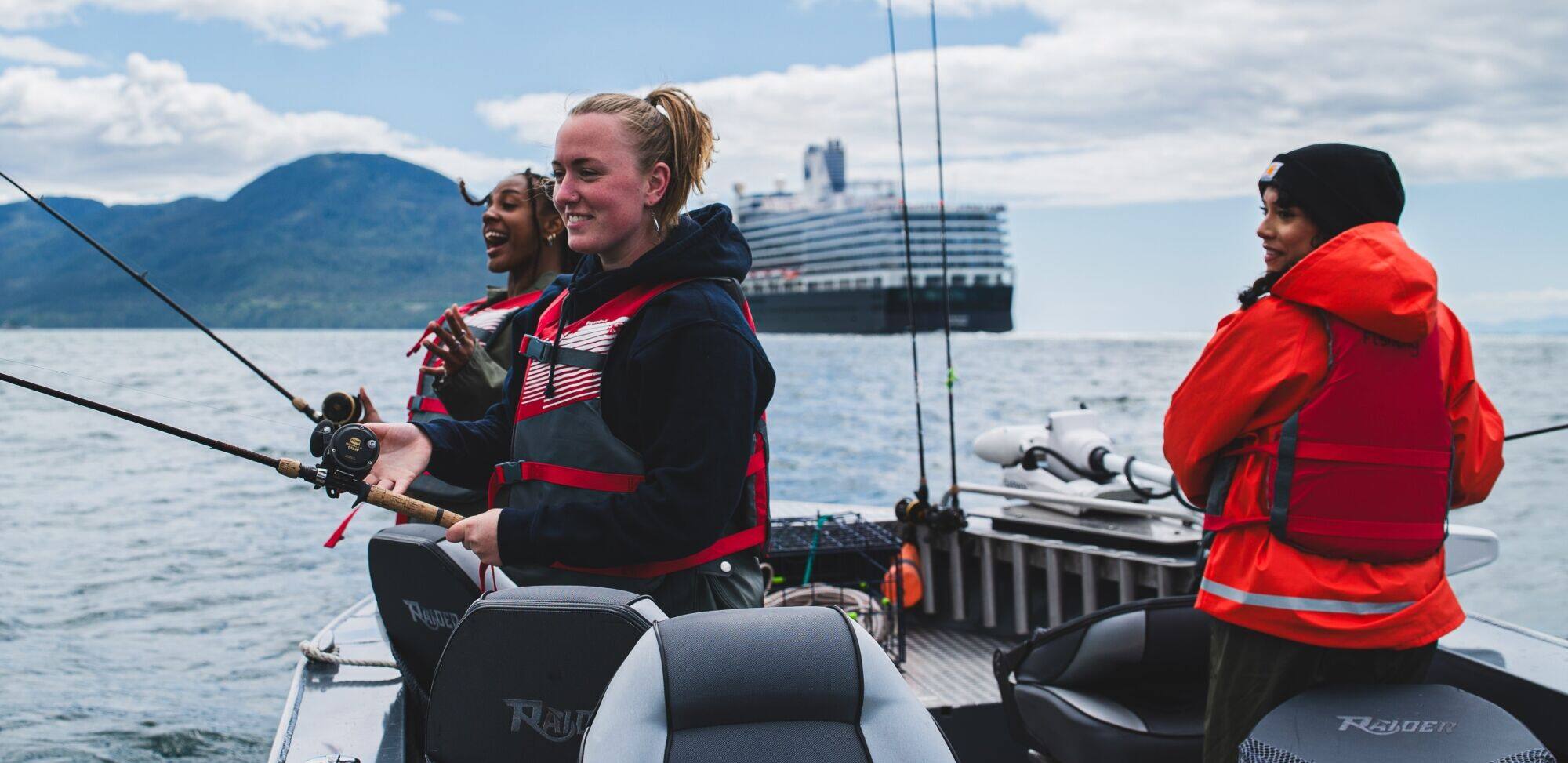 People fishing from a small boat with a cruise ship in the background.