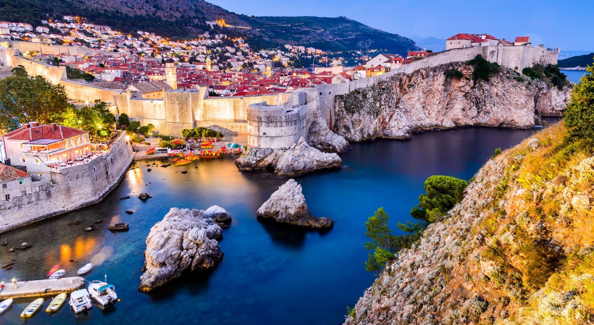 Dubrovnik Old Town and medieval city walls along the Adriatic Sea at dusk.