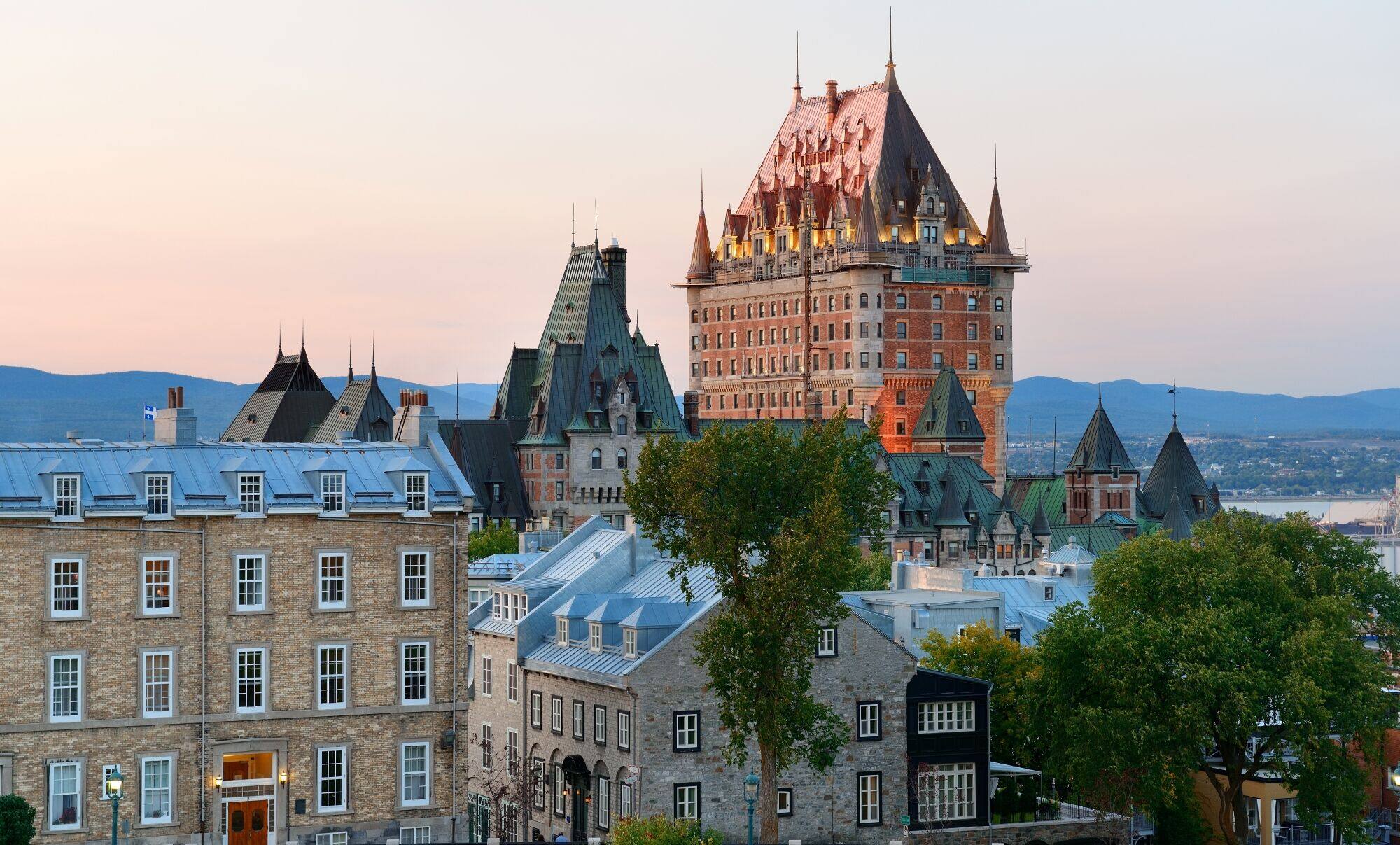 Château Frontenac overlooking Old Quebec with historic stone buildings at sunset.