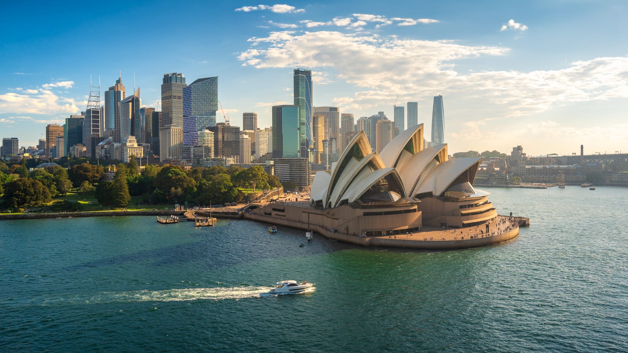 Sydney Opera House on the harbor with the city skyline in the background.