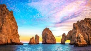 ideal-cruise-lenght-blog-1 Rocky sea arches and towering cliffs at sunset over blue ocean waters.