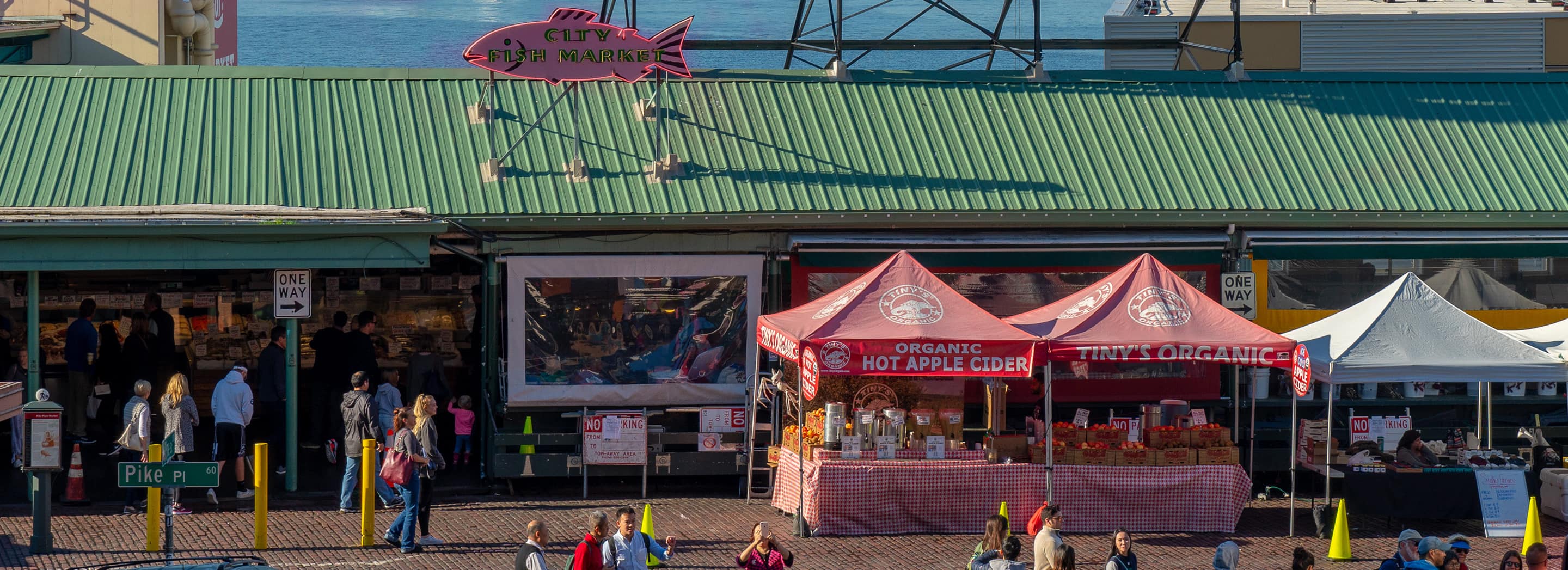Stalls at Seattle's Pike Place Market featuring the City Fish Market and an organic hot apple cider stand.